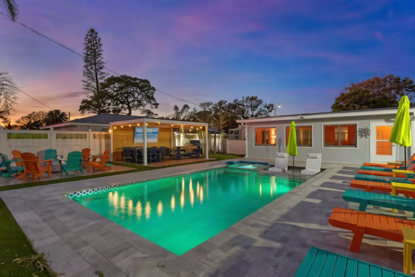 Pool lit green at twilight with in-water loungers and pavilion at Pickleball Resort, Bradenton, Florida