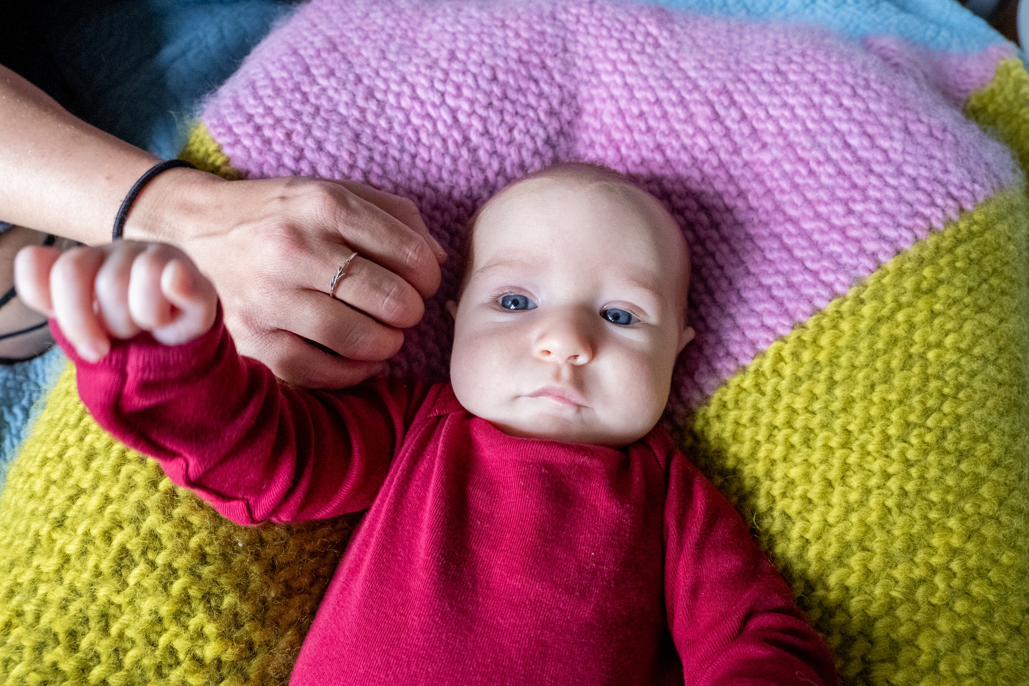 newborn-laying-on-pink-and-yellow-knitted-blanket-katt-jones-photography