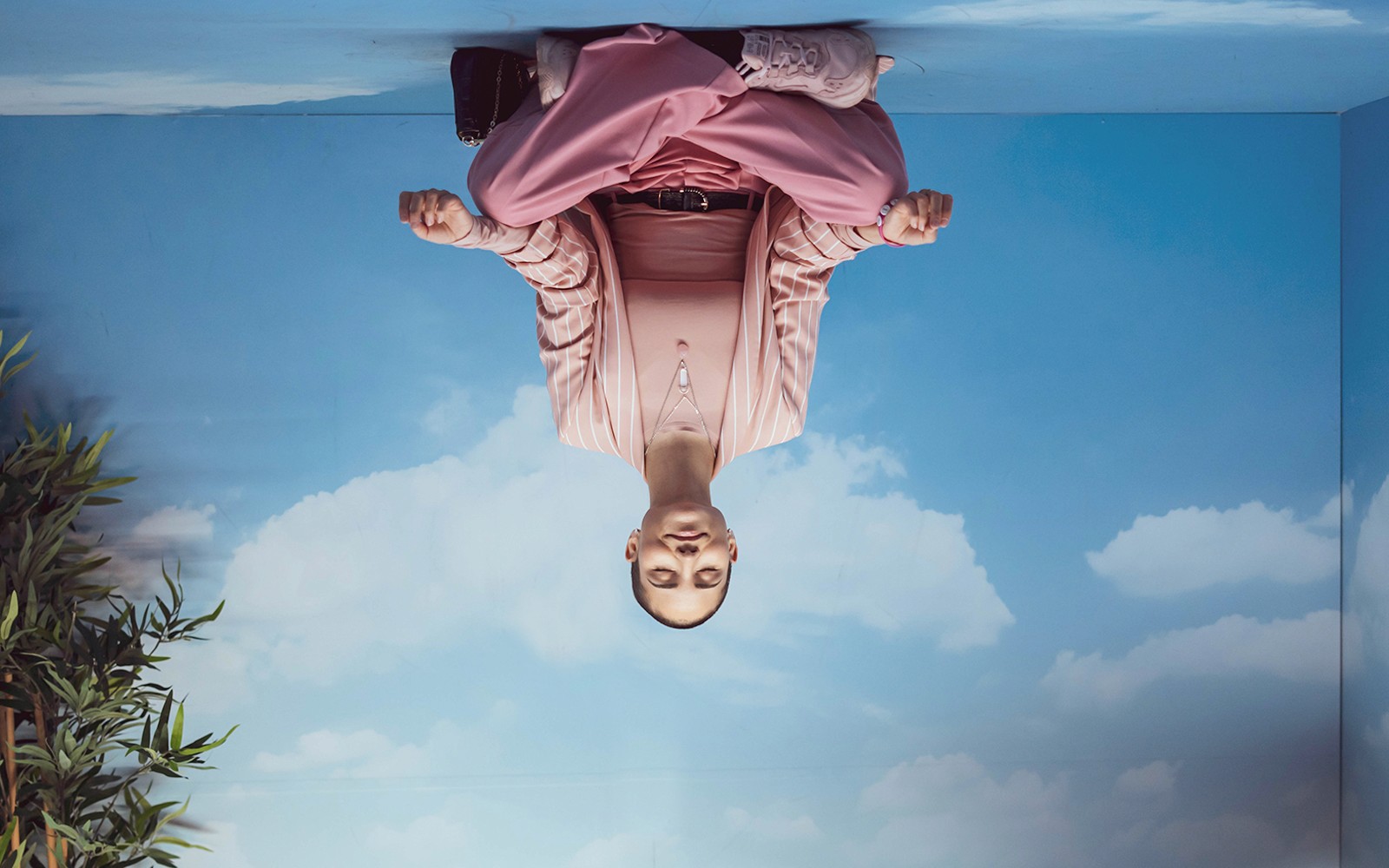 Személy meditál egy szobában, ahol az ég és a felhők láthatók a Pink Palace-ban.