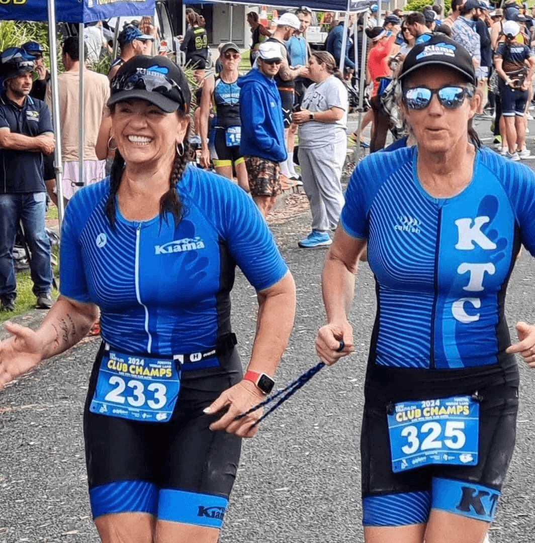 Lily running over the finish line with her guide, Jodie, holding a tether at the NSW triathlon state championships.