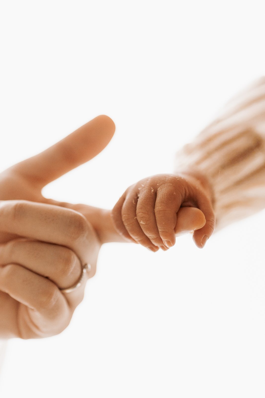 Hand der Mutter hält winzige Babyhand