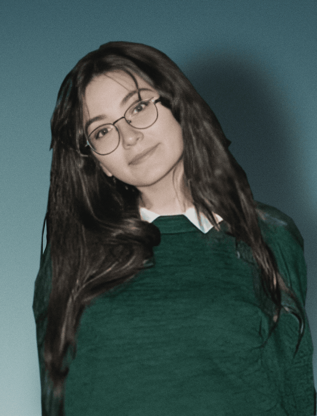A young man with dark hair smiles at the camera, set against a modern indoor background.