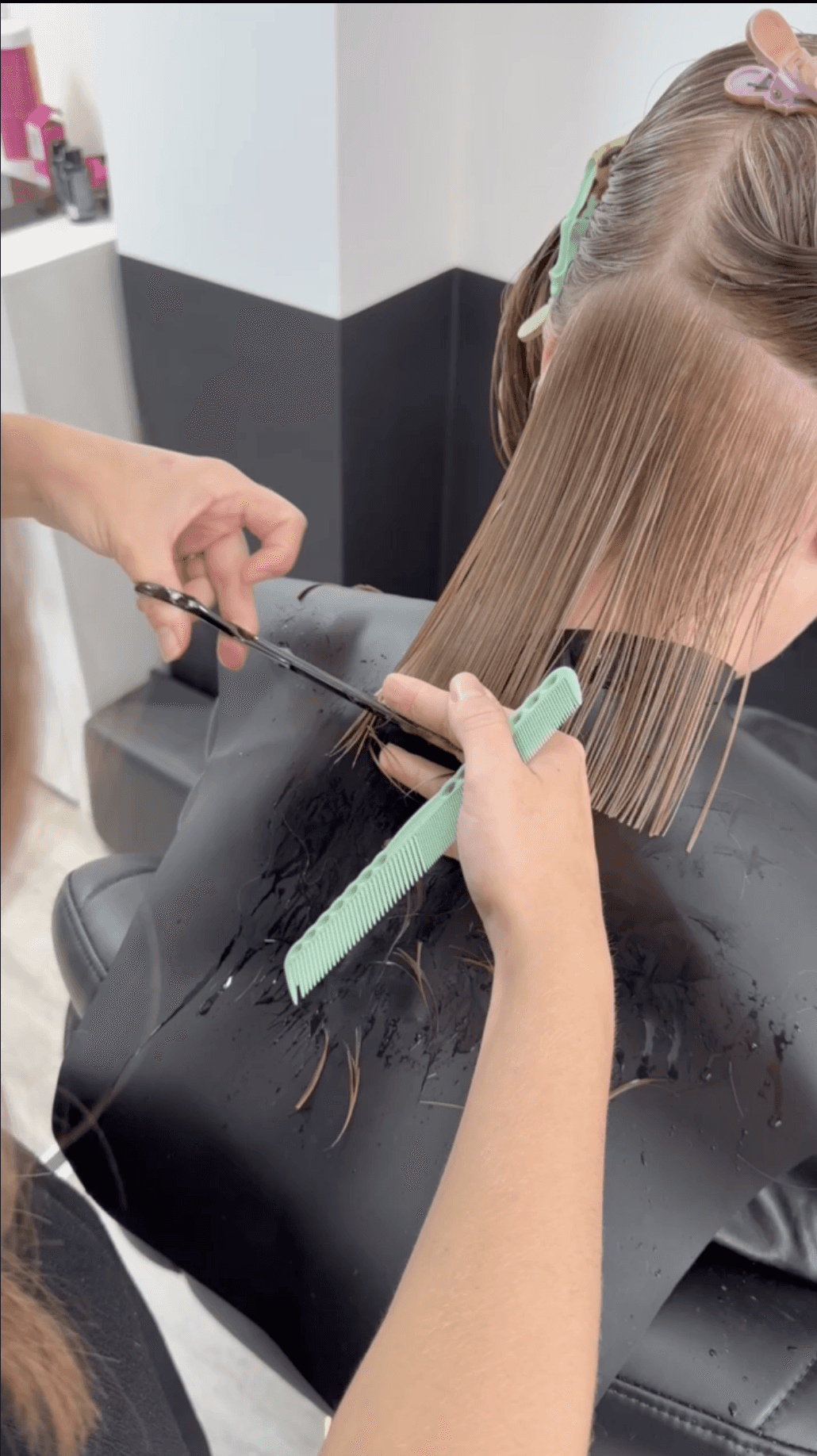 Woman with mid-length black hair getting their hair cut at hair salon
