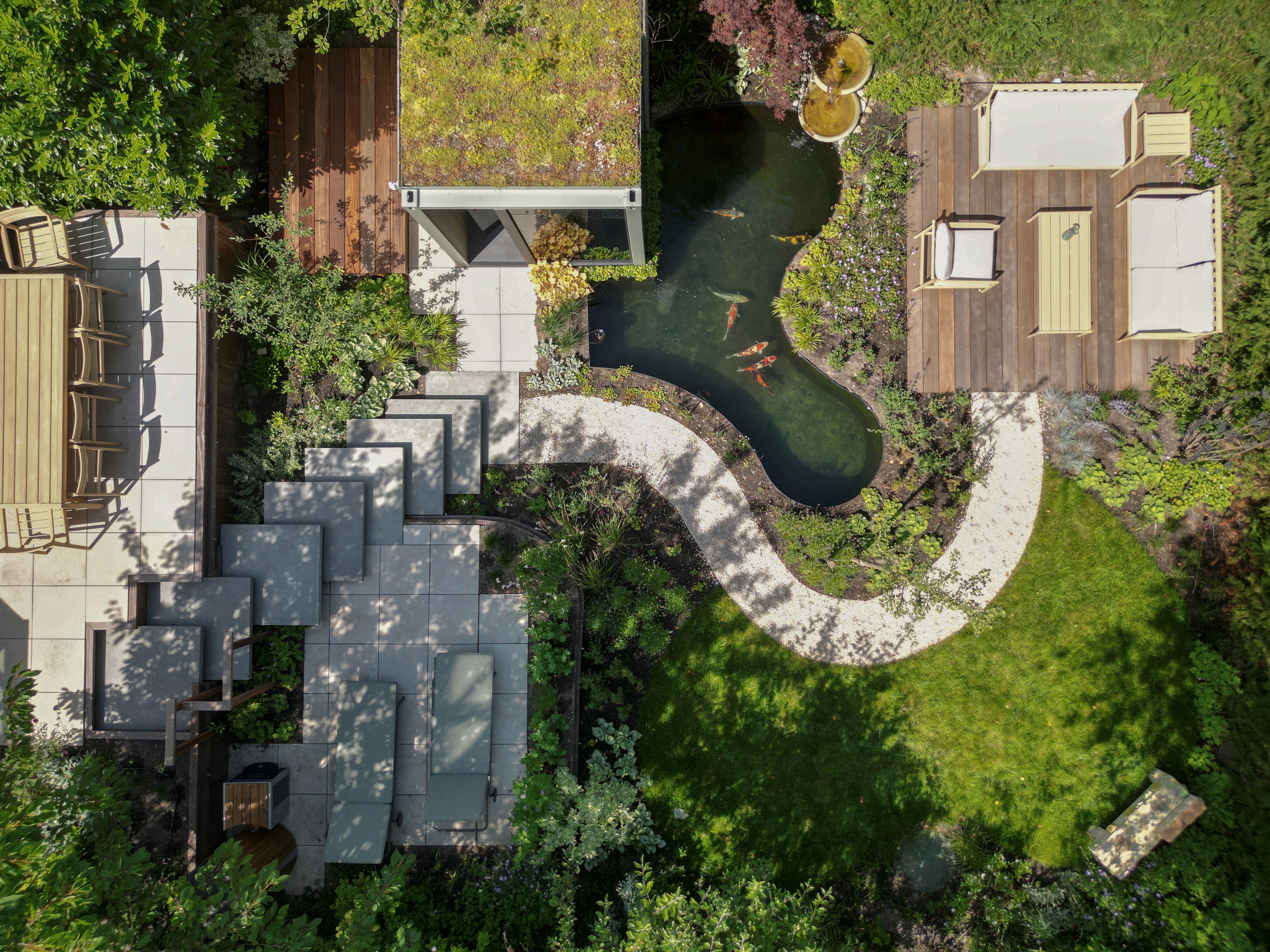 Modern glass and wood cabin with a cozy outdoor deck featuring wicker furniture, surrounded by lush green trees and a serene forest setting.