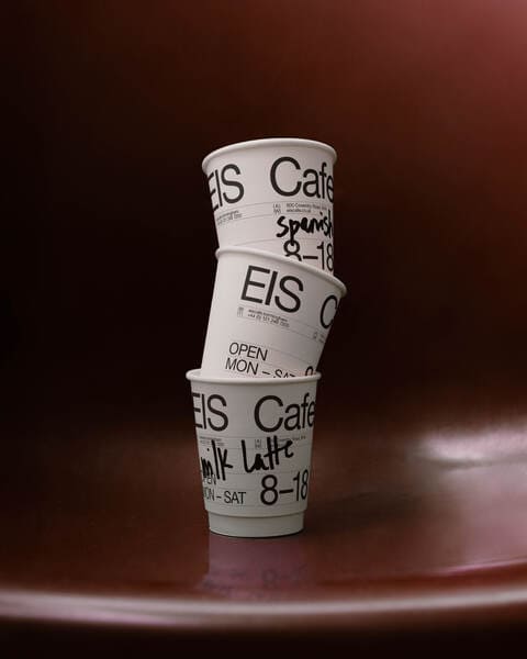 A photo of 3 coffee cups stacked one on top of the other against a dark red background.