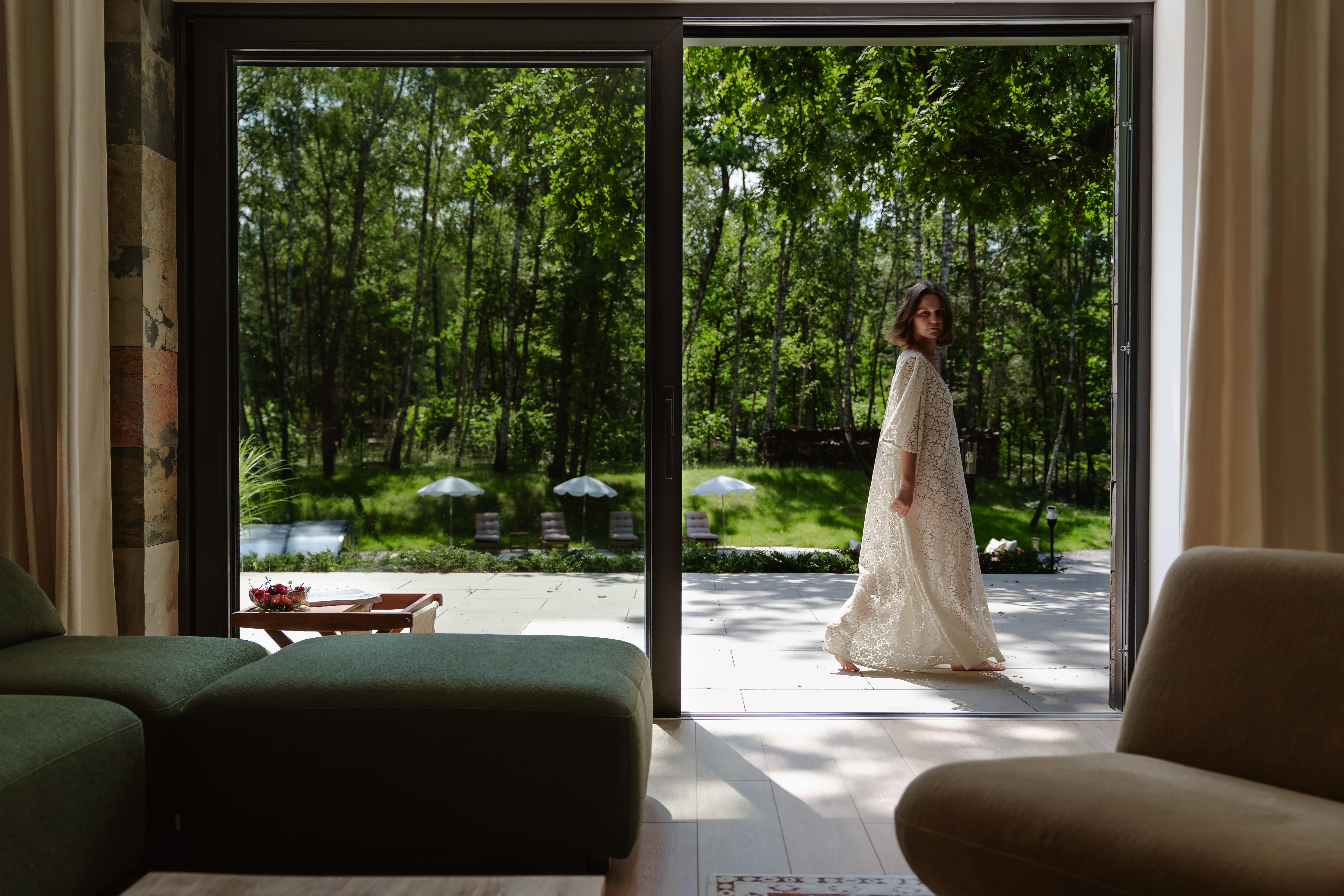 A quiet sunlit living room with natural plaster walls, a sofa, and warm editorial shadows.