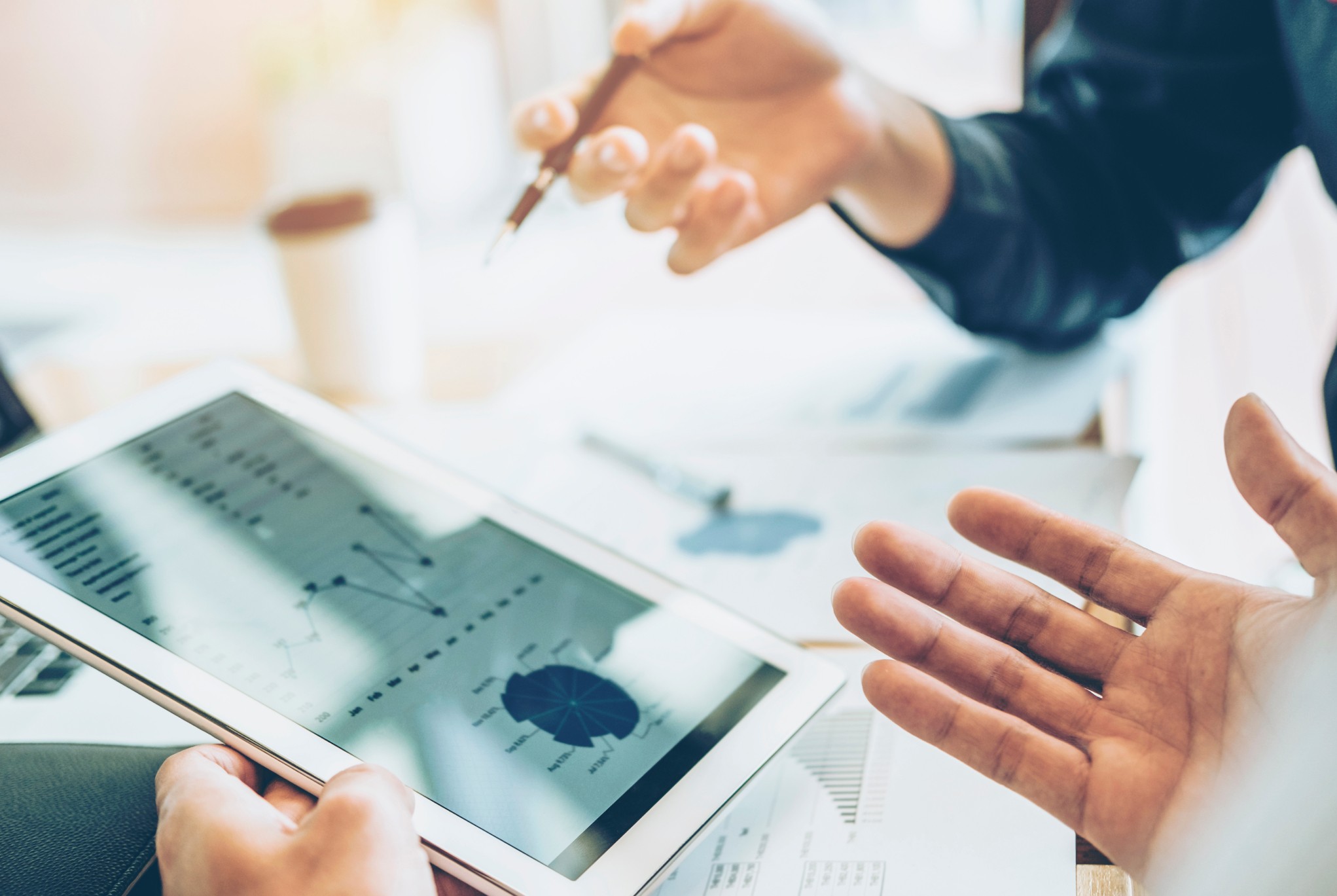 Close-up of hands discussing financial data on a tablet, highlighting financial challenges in healthcare and the need for data-driven decision-making.