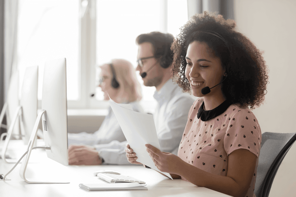 SPIN selling: Smiling woman wearing a headset while reading a document