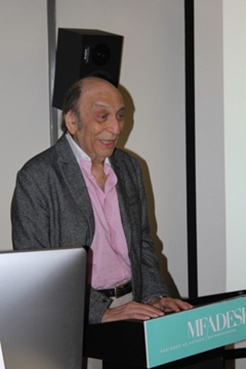 a man with a grey coat and a pink shirt is playing on an electronic piano