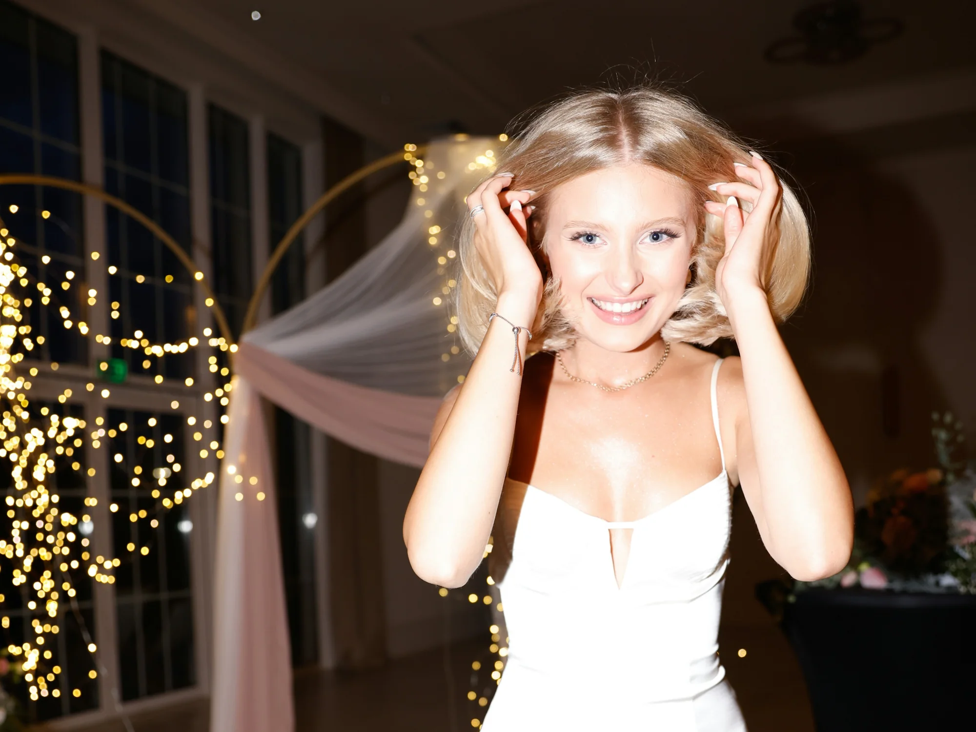Honey laughing with her hands in her hair at a party