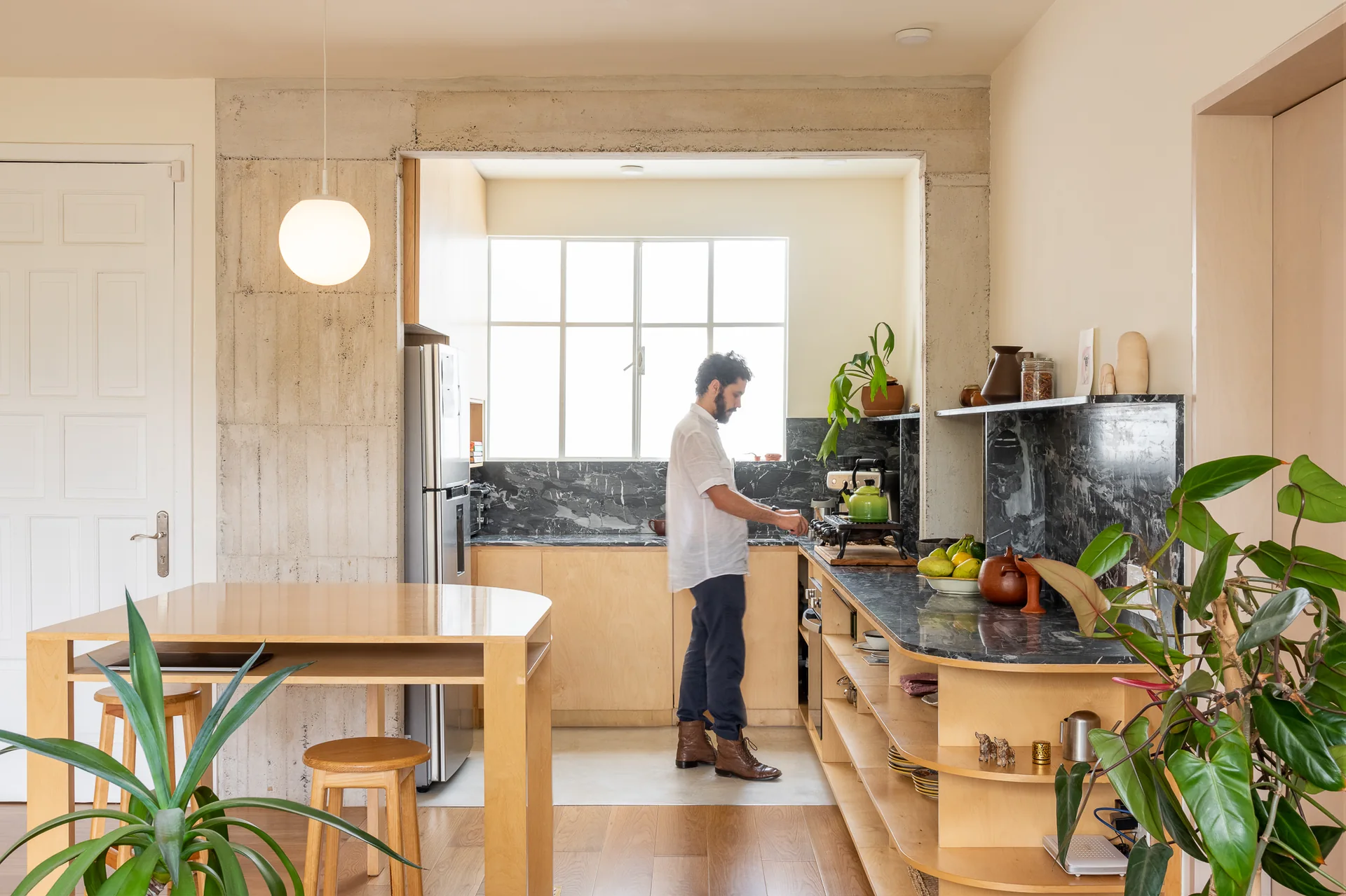 Persona cocinando en la cocina junto al comedor de madera con plantas