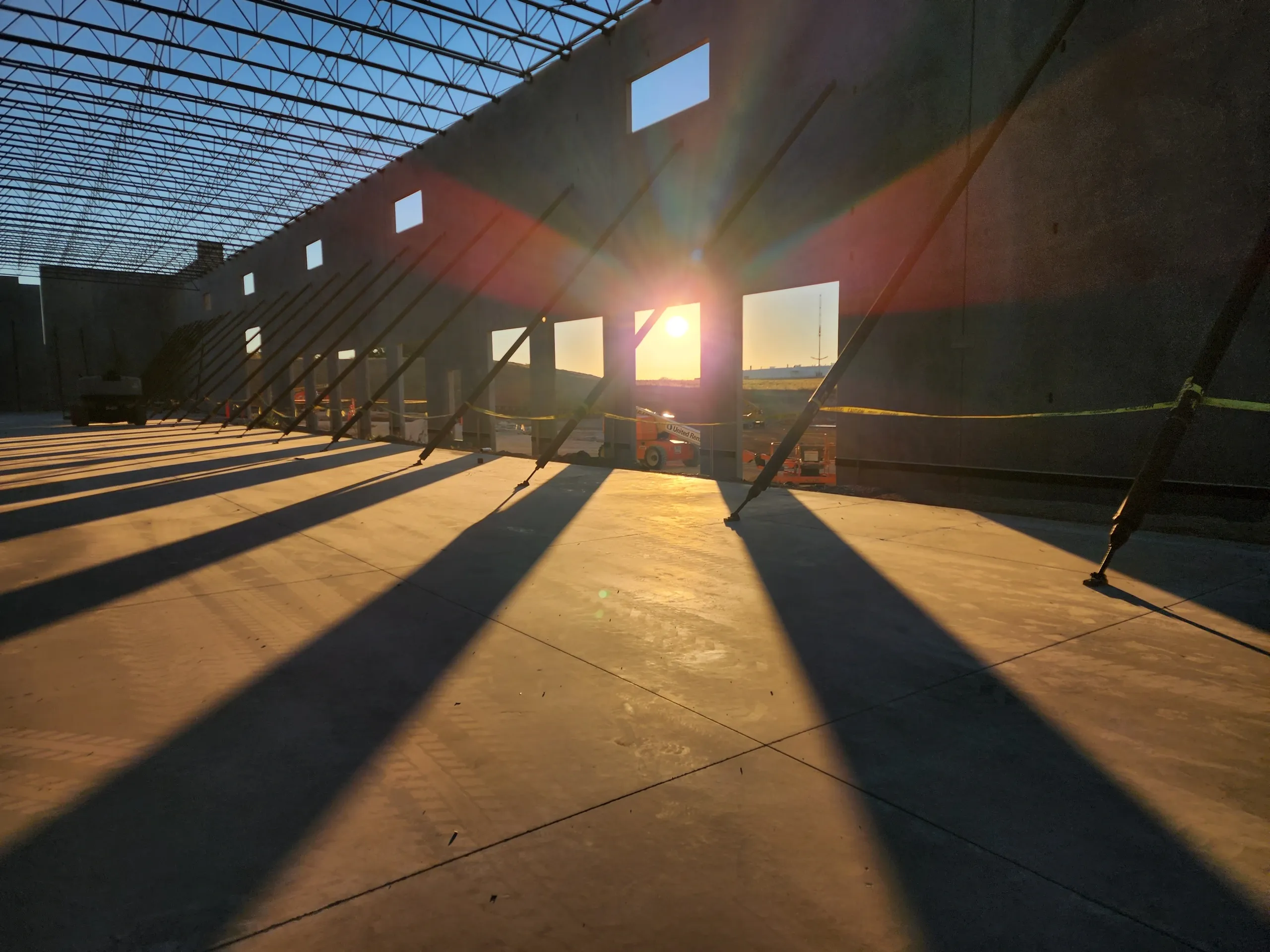 Sunlight streaming into an empty industrial warehouse under construction