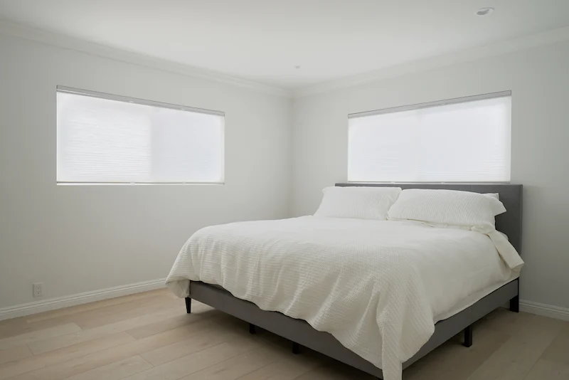 Bedroom with two windows letting in natural light. Vinyl flooring. Photo by Todd Huge.