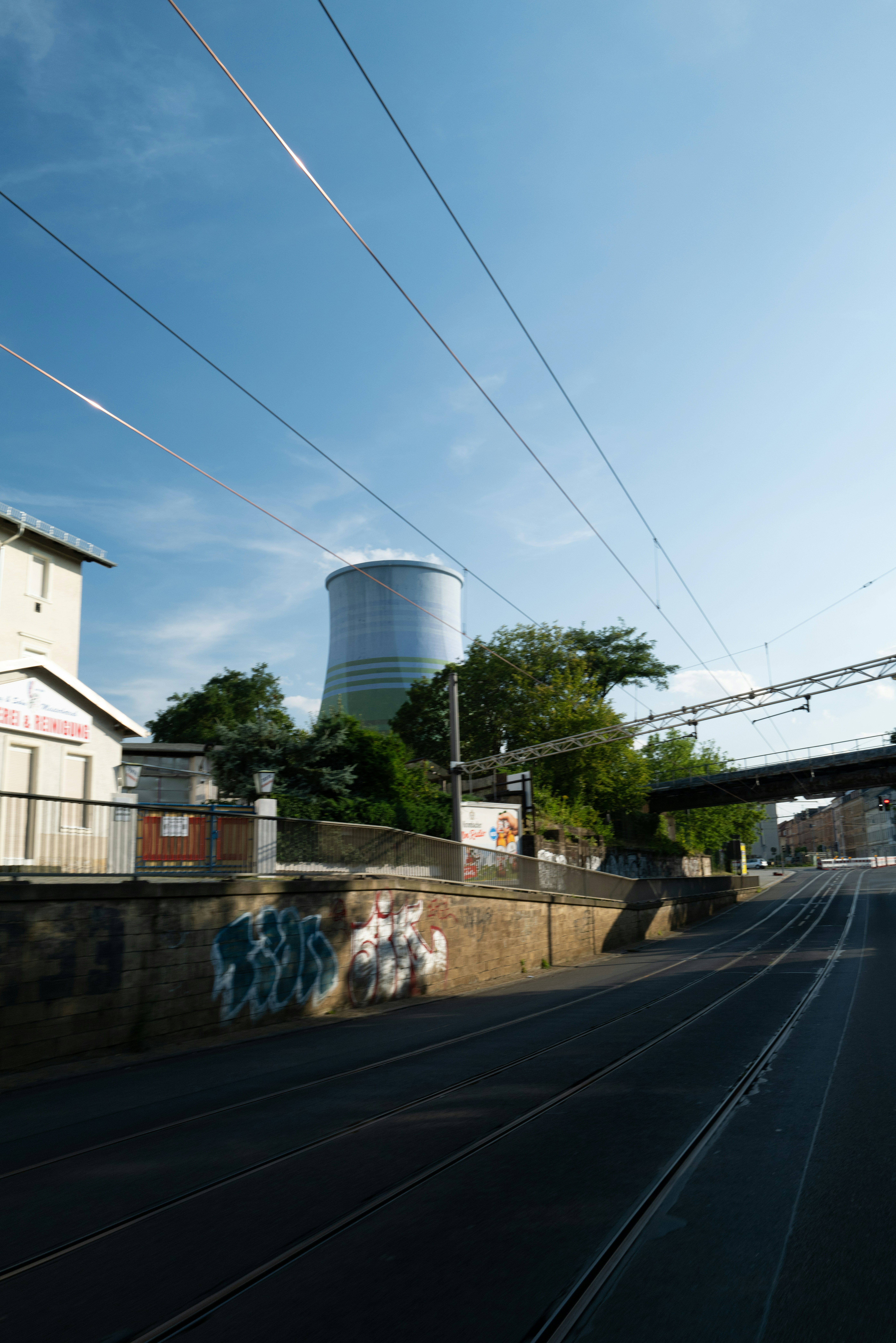 A train traveling past a power plant next to a bridge