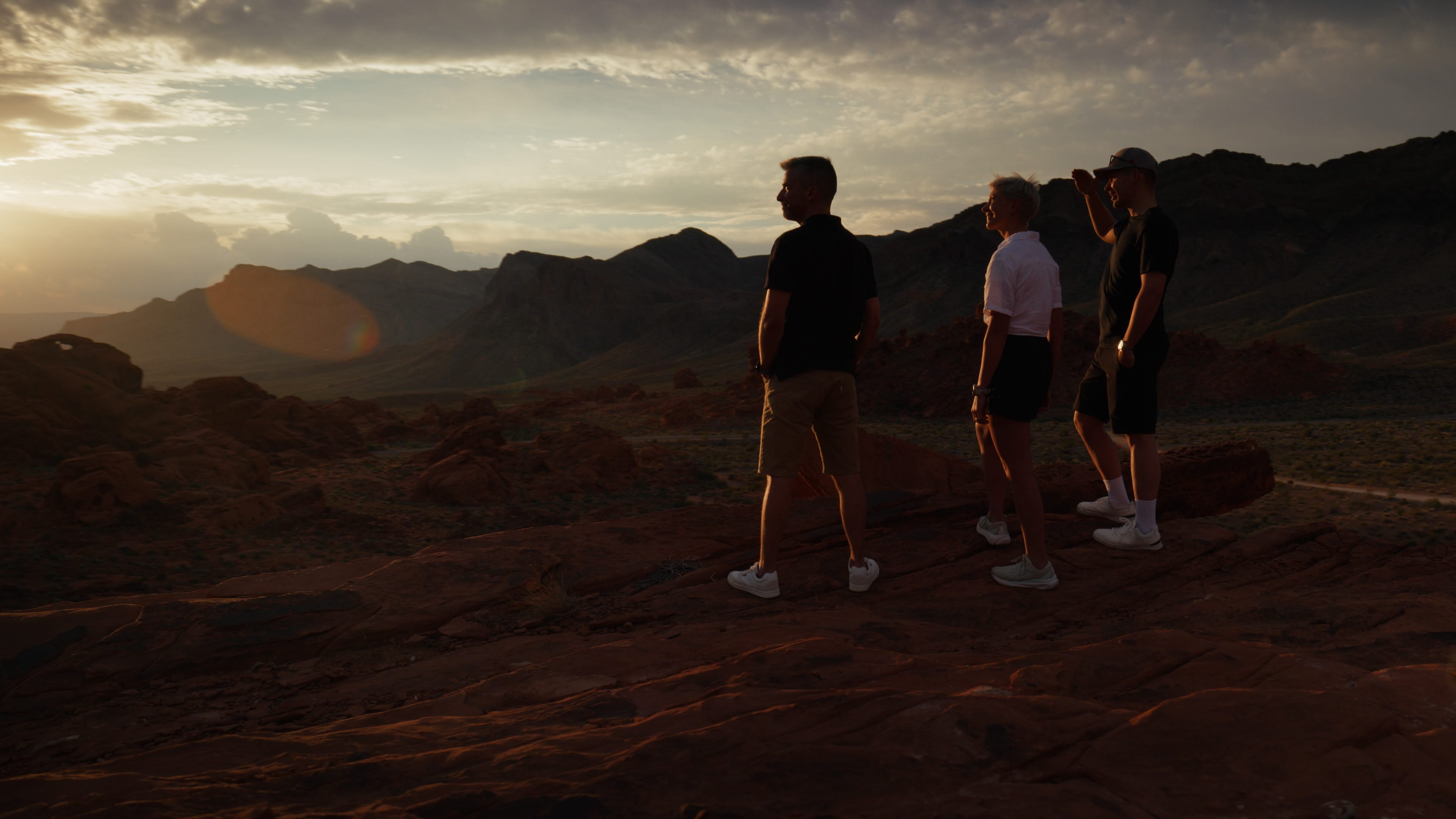 A film director sits in a chair facing a bustling, warmly lit night market scene. A camera setup is nearby, capturing the energetic atmosphere.