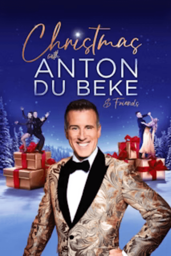 Christmas event with Anton Du Beke and dancers on gift boxes in snowy landscape.