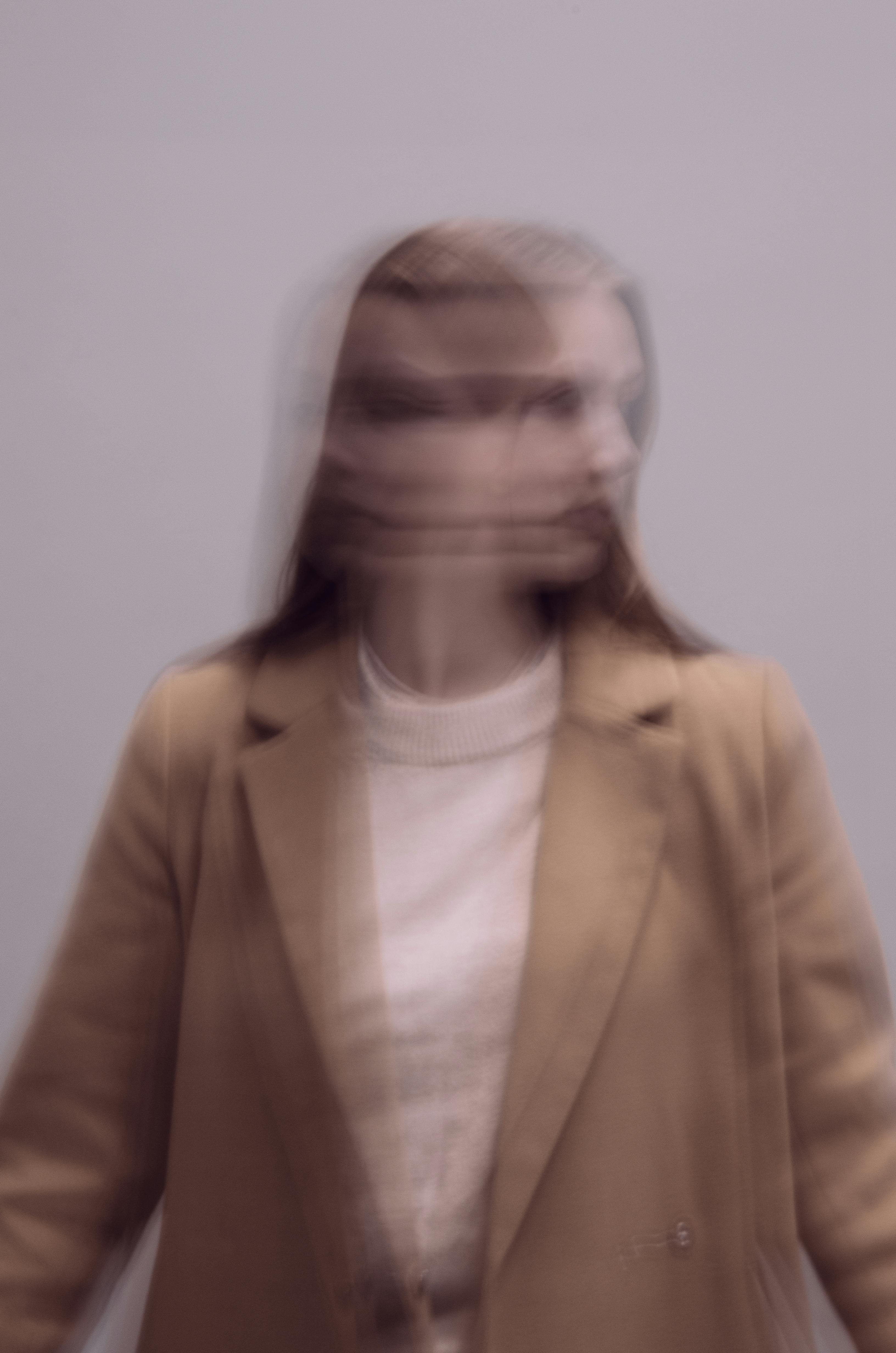 Woman in a light suit sitting thoughtfully against a terracotta wall