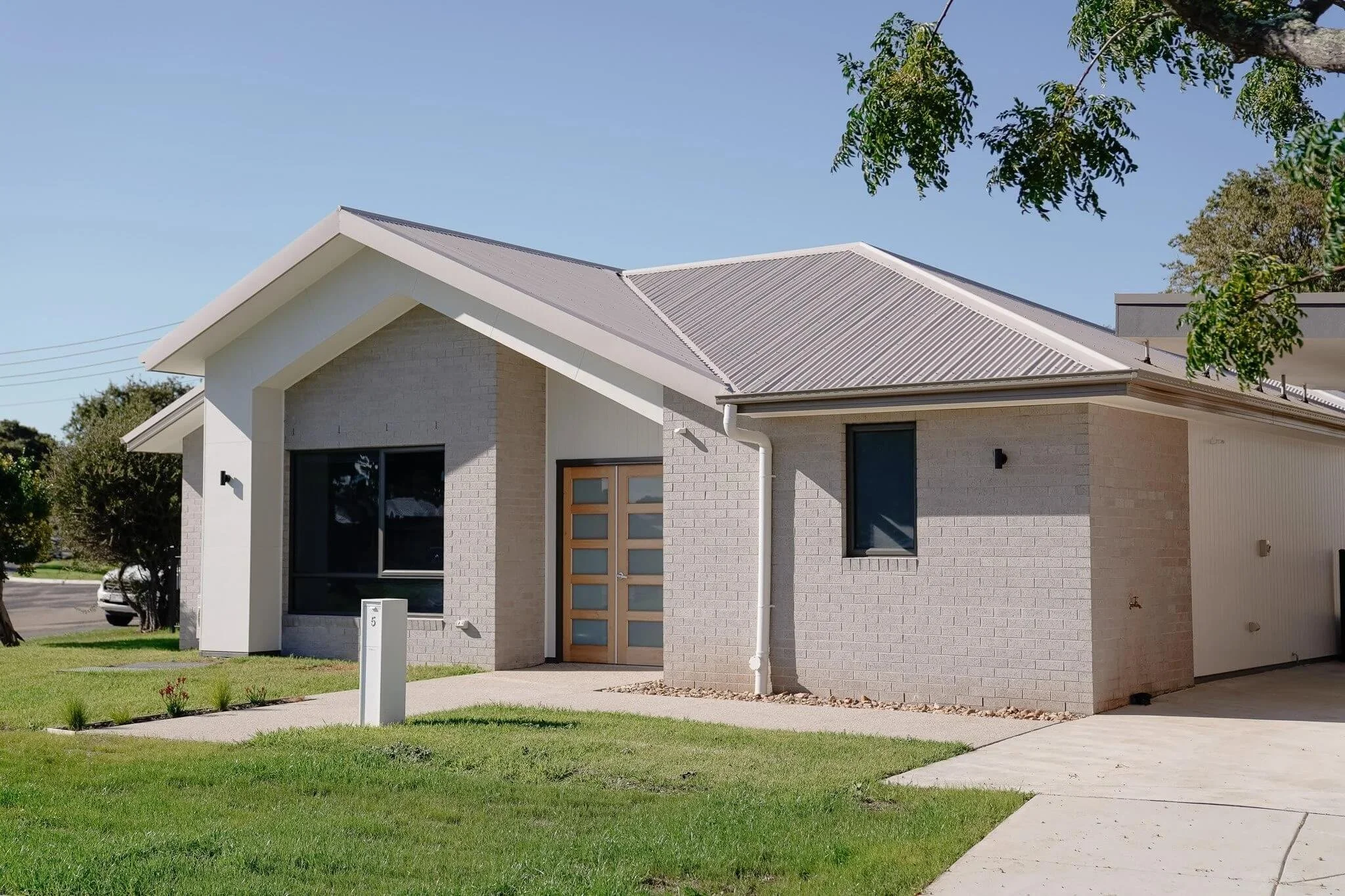 Modern single-story brick house with sloped roof on a sunny day.