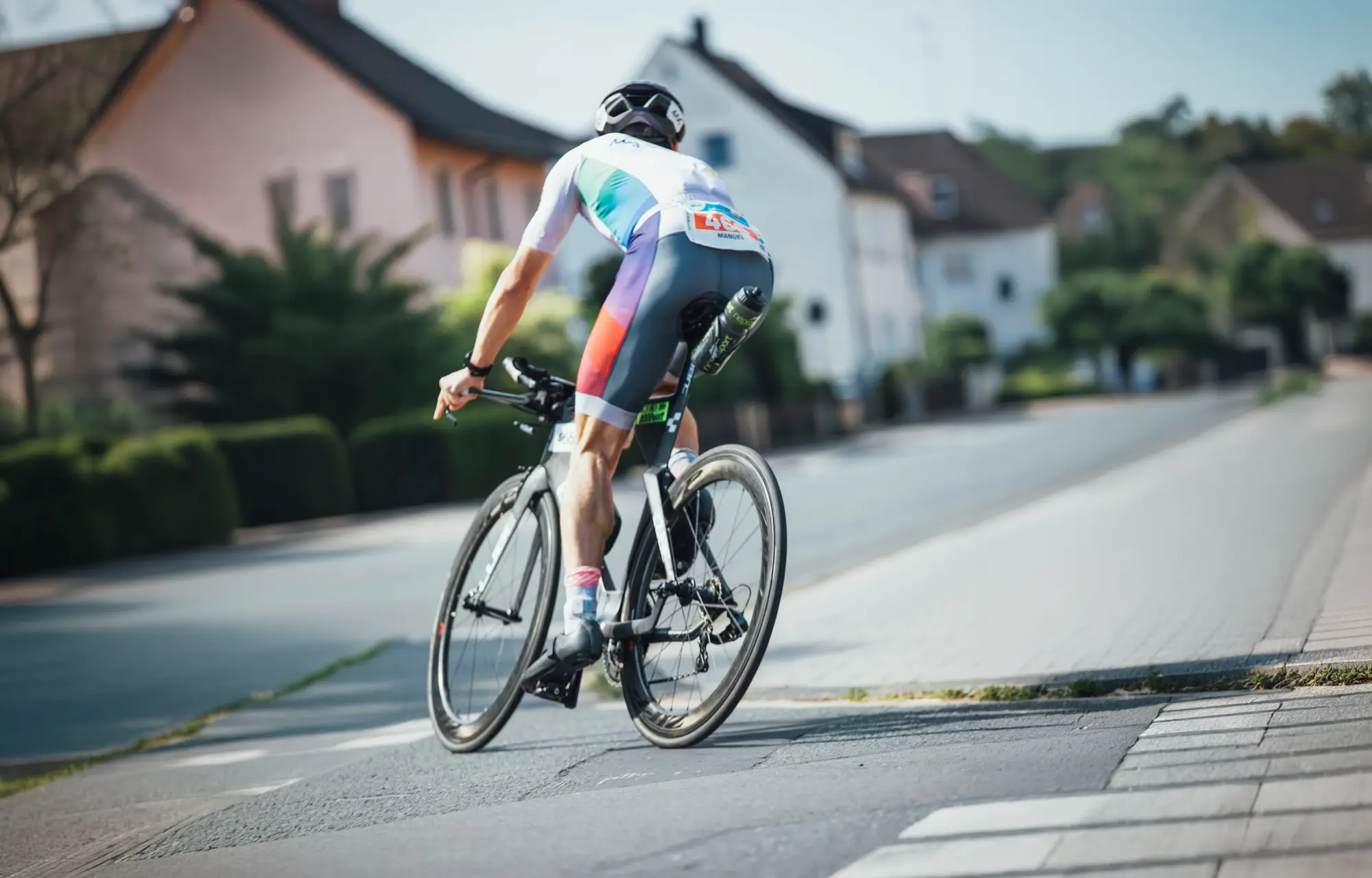 Triathlete riding a tri bike through a quiet village street during the bike leg of an Ironman 70.3 race