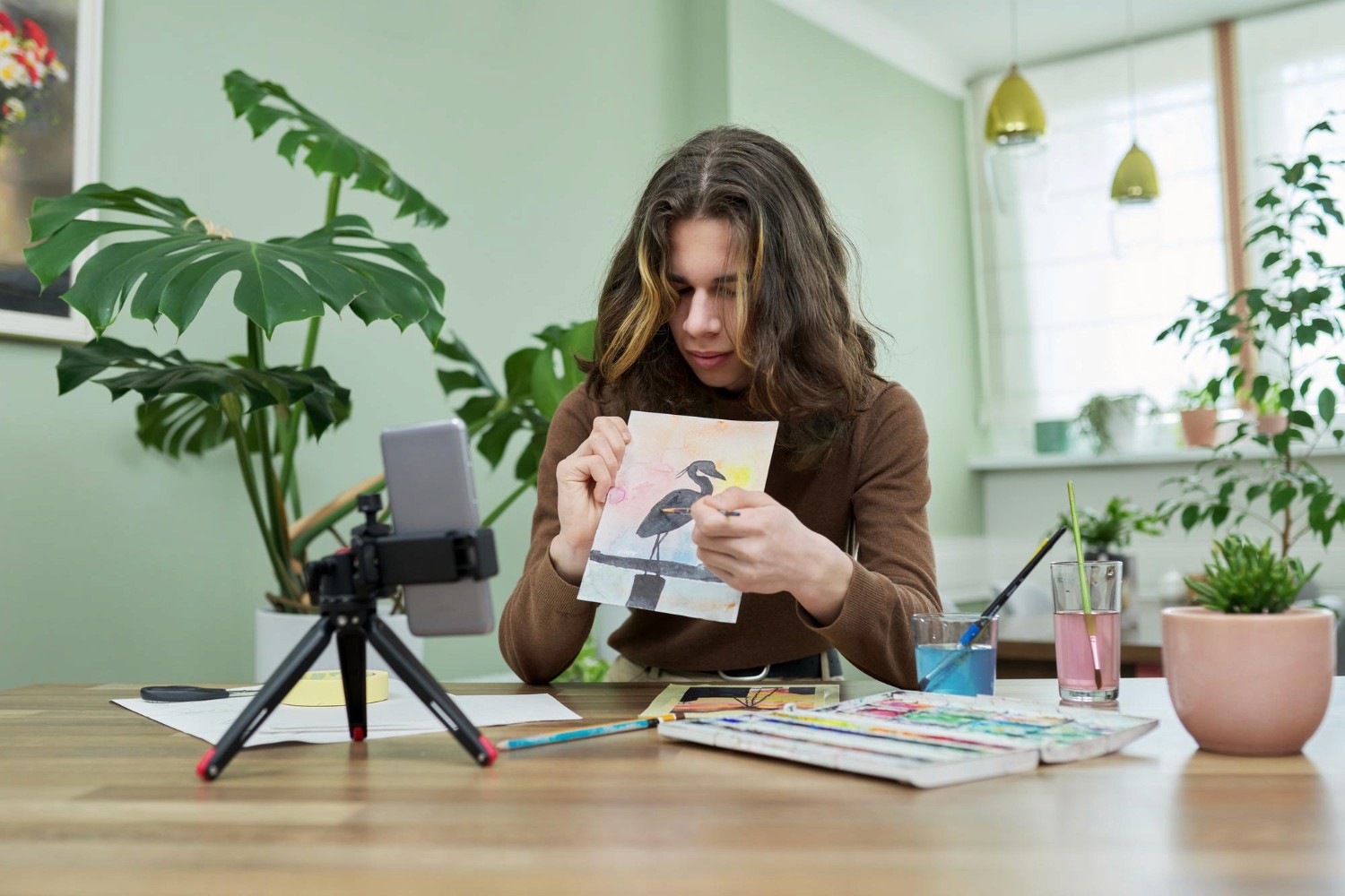  A woman seated at a table holds a piece of paper, appearing focused and engaged in her task.