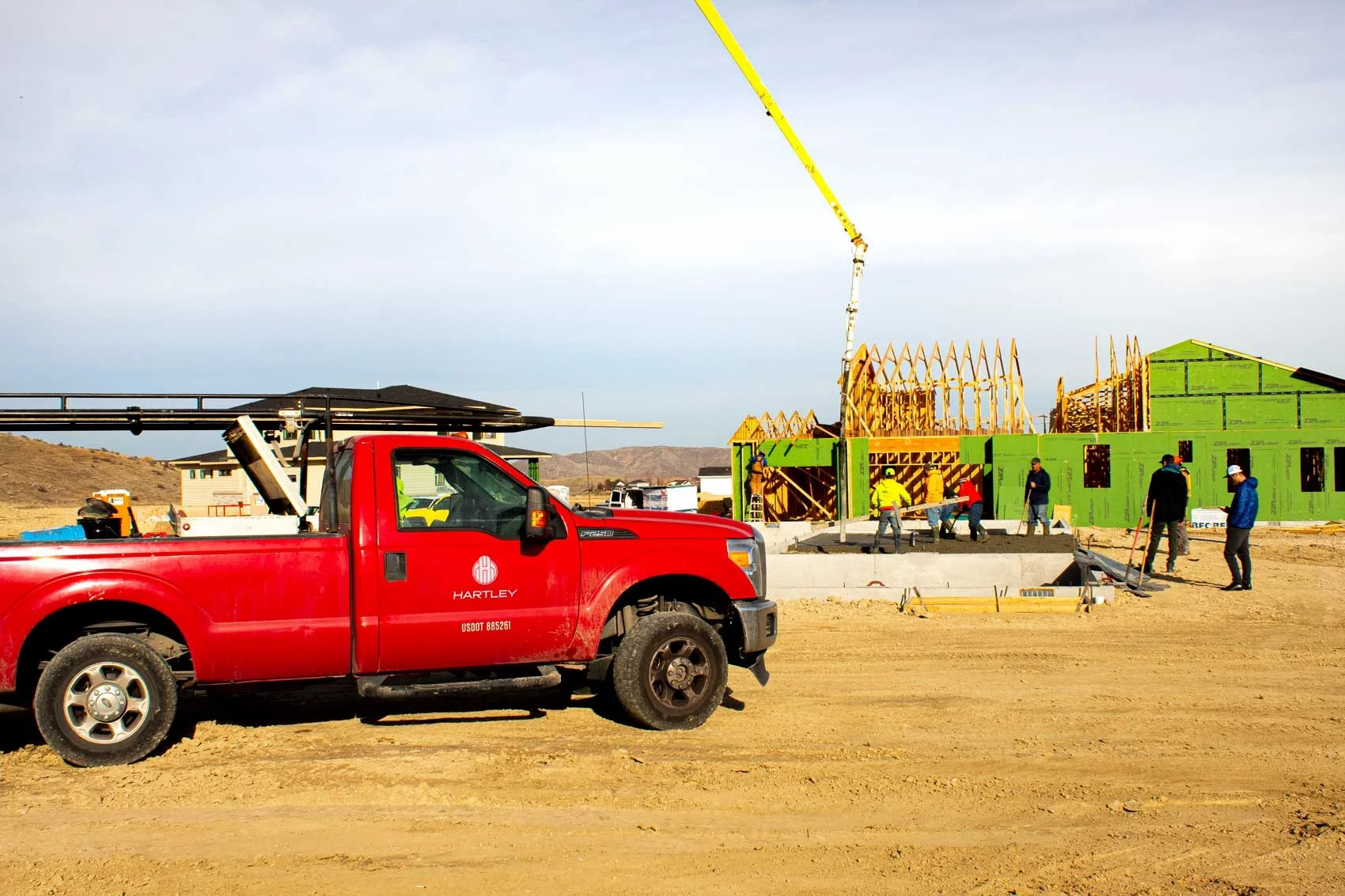 A red Hartley Concrete truck parked at a residential construction site 