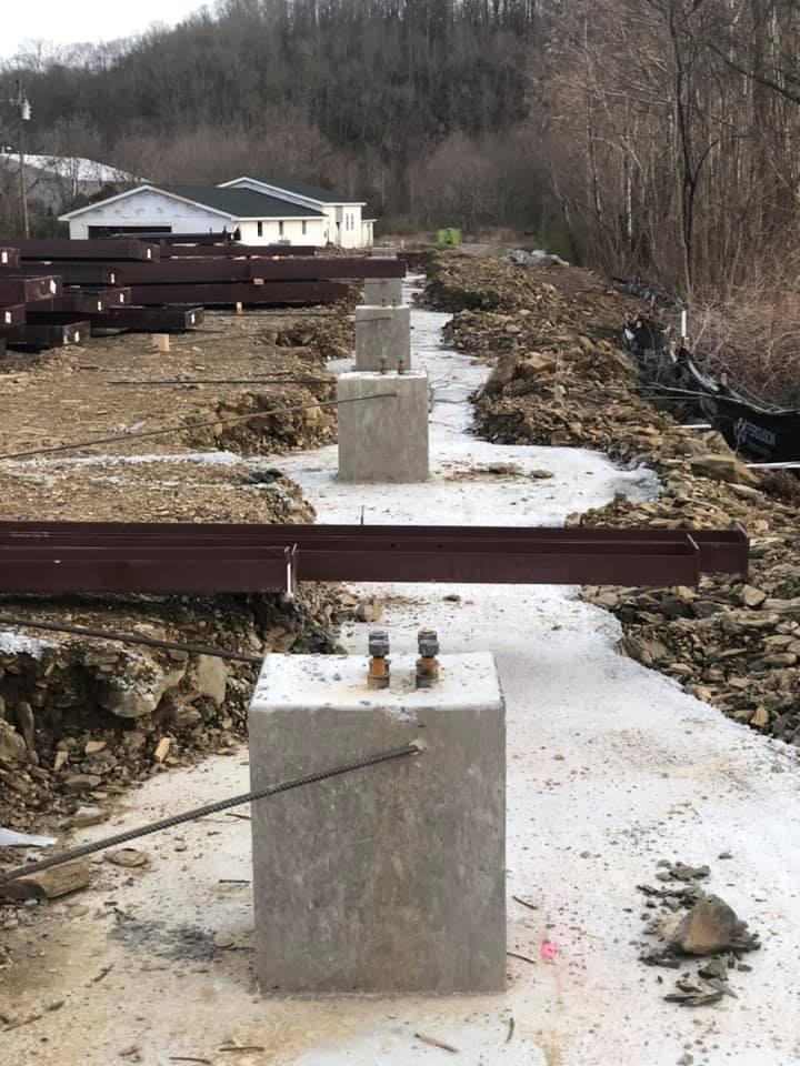 Several concrete footers with metal beams waiting to be installed