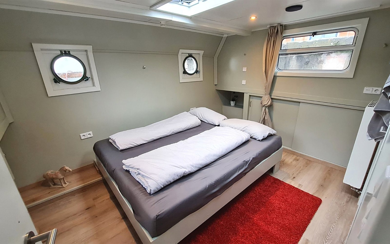 Gezellige hutinterieur tijdens een Spree riviercruise, met een tweepersoonsbed en patrijspoorten.