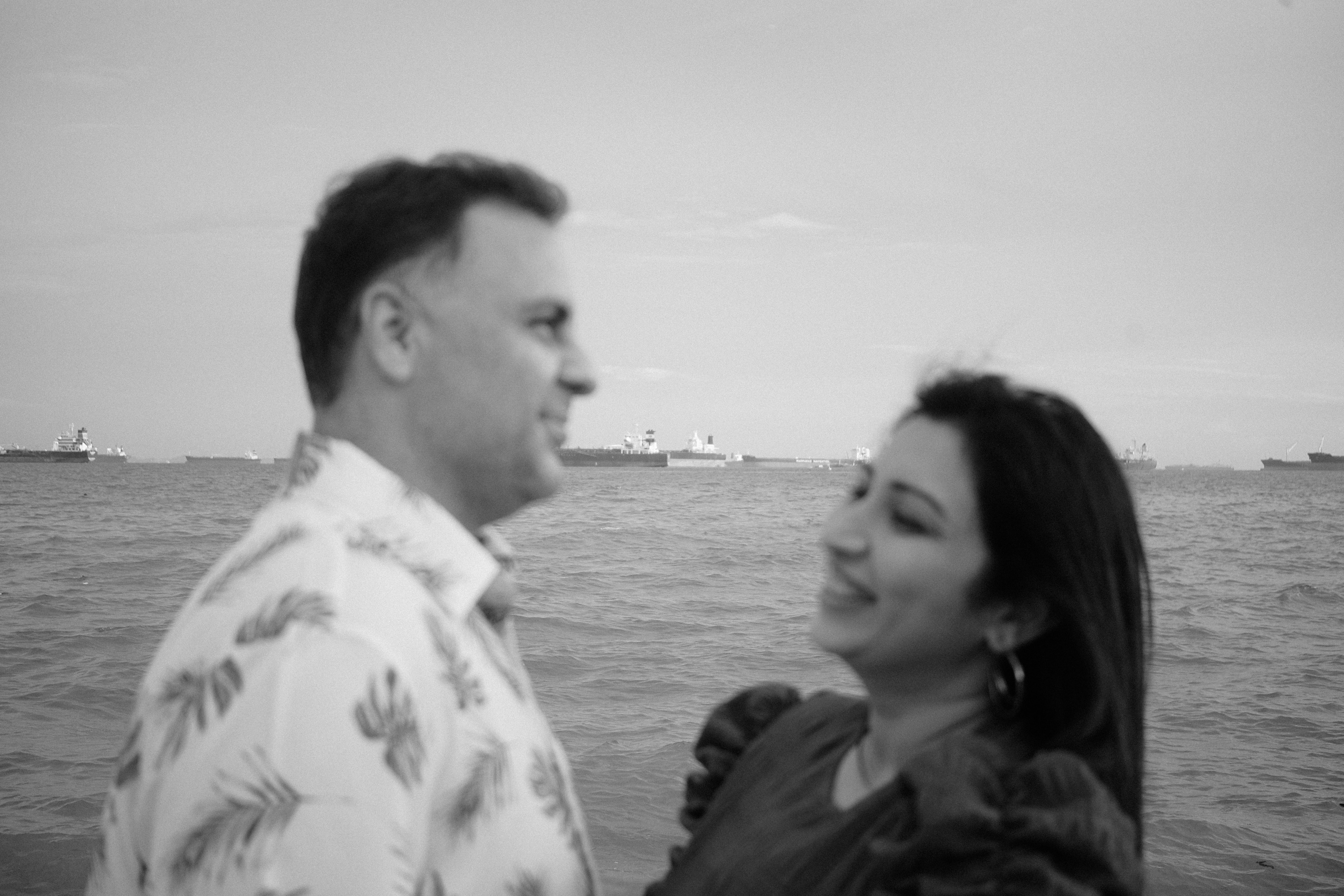Couple looking intently into each other's eyes with the Singapore sea in the background at sunset.
