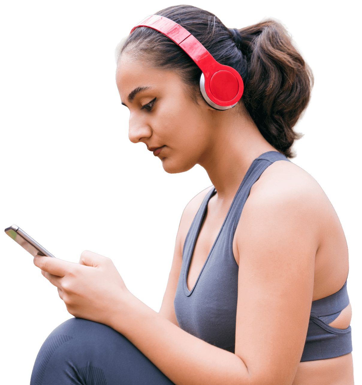 Woman in a sports bra using her phone with red headphones