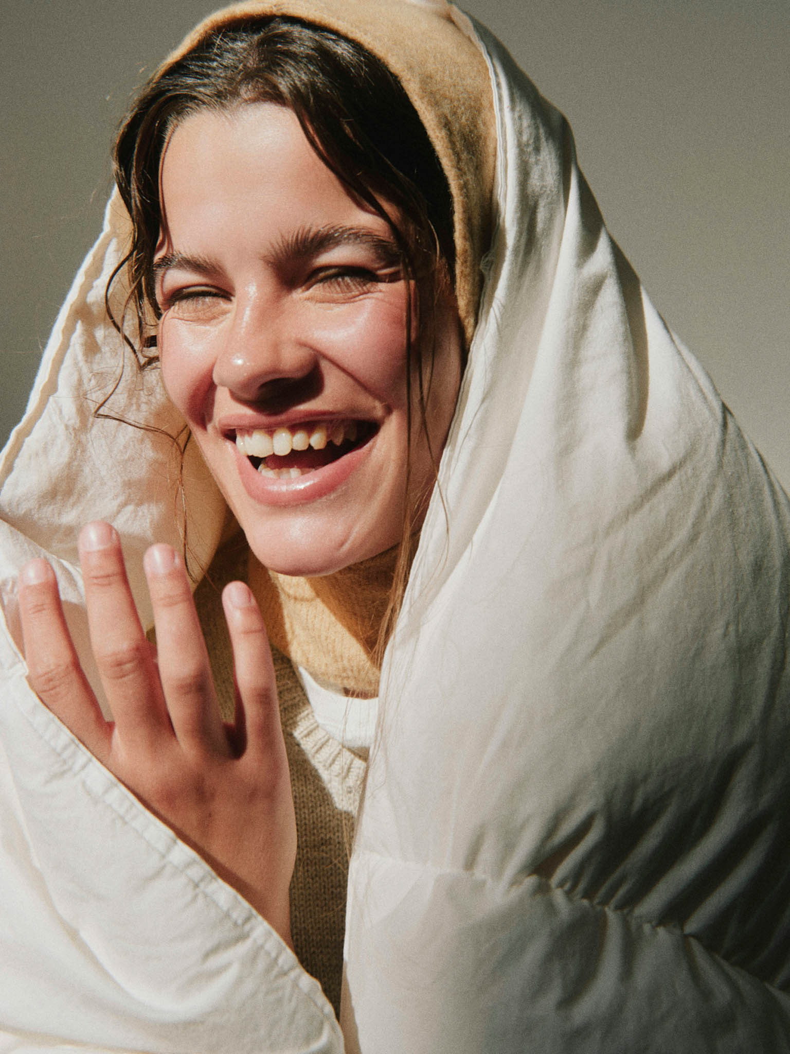 femme riant, la tête dans une couette