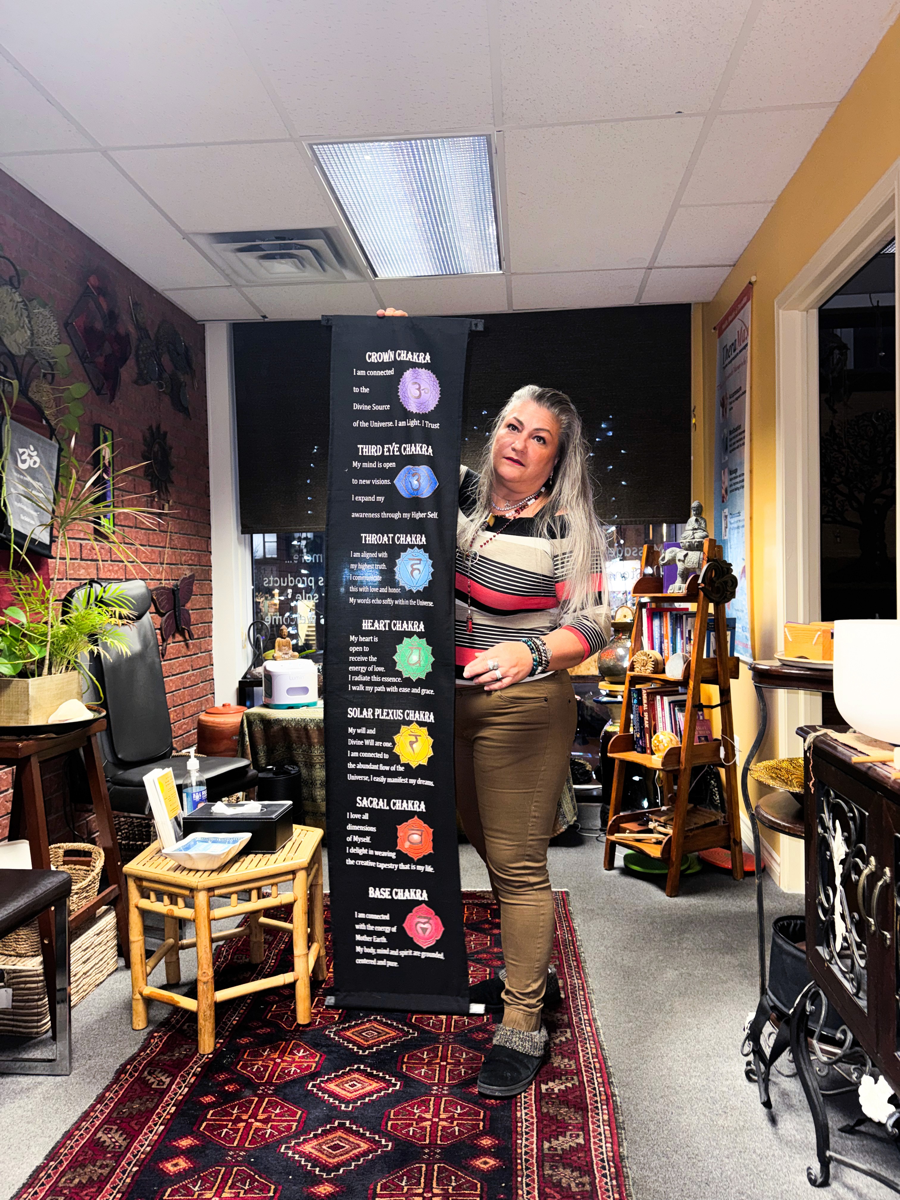 A circle of people sitting cross-legged, meditating with hands in a prayer position. Soft, warm lighting.