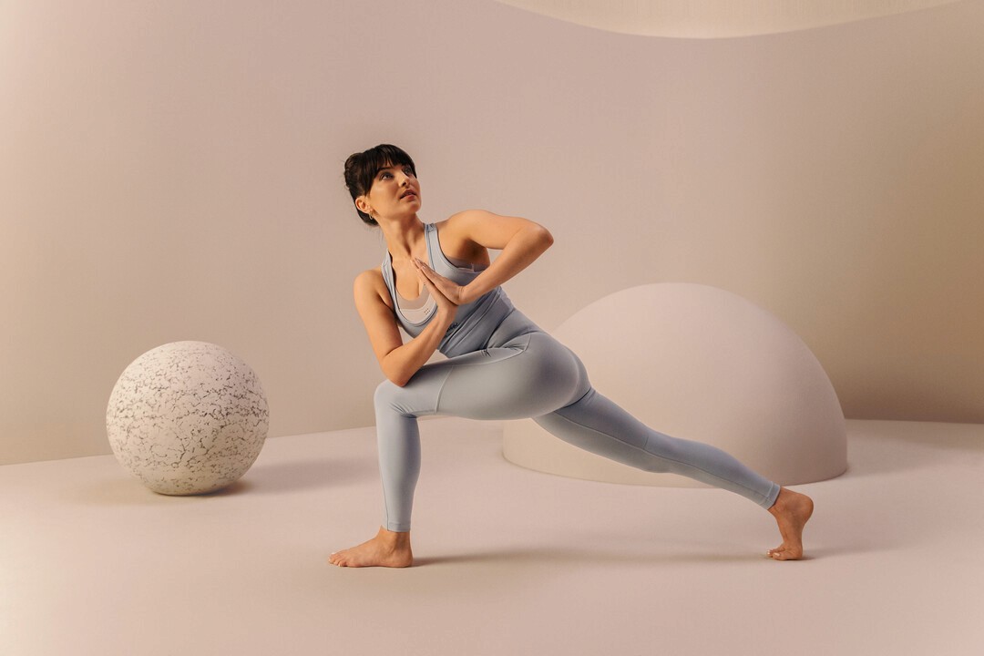 Eine konzentrierte Frau in hellblauer Sportkleidung macht eine Pilates-Übung.
