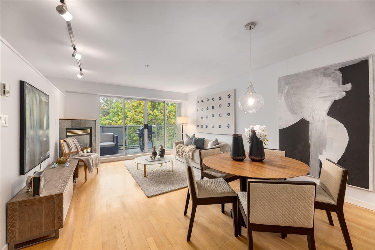 Modern dining area with a wooden table, stylish chairs, and large windows showcasing greenery outside.