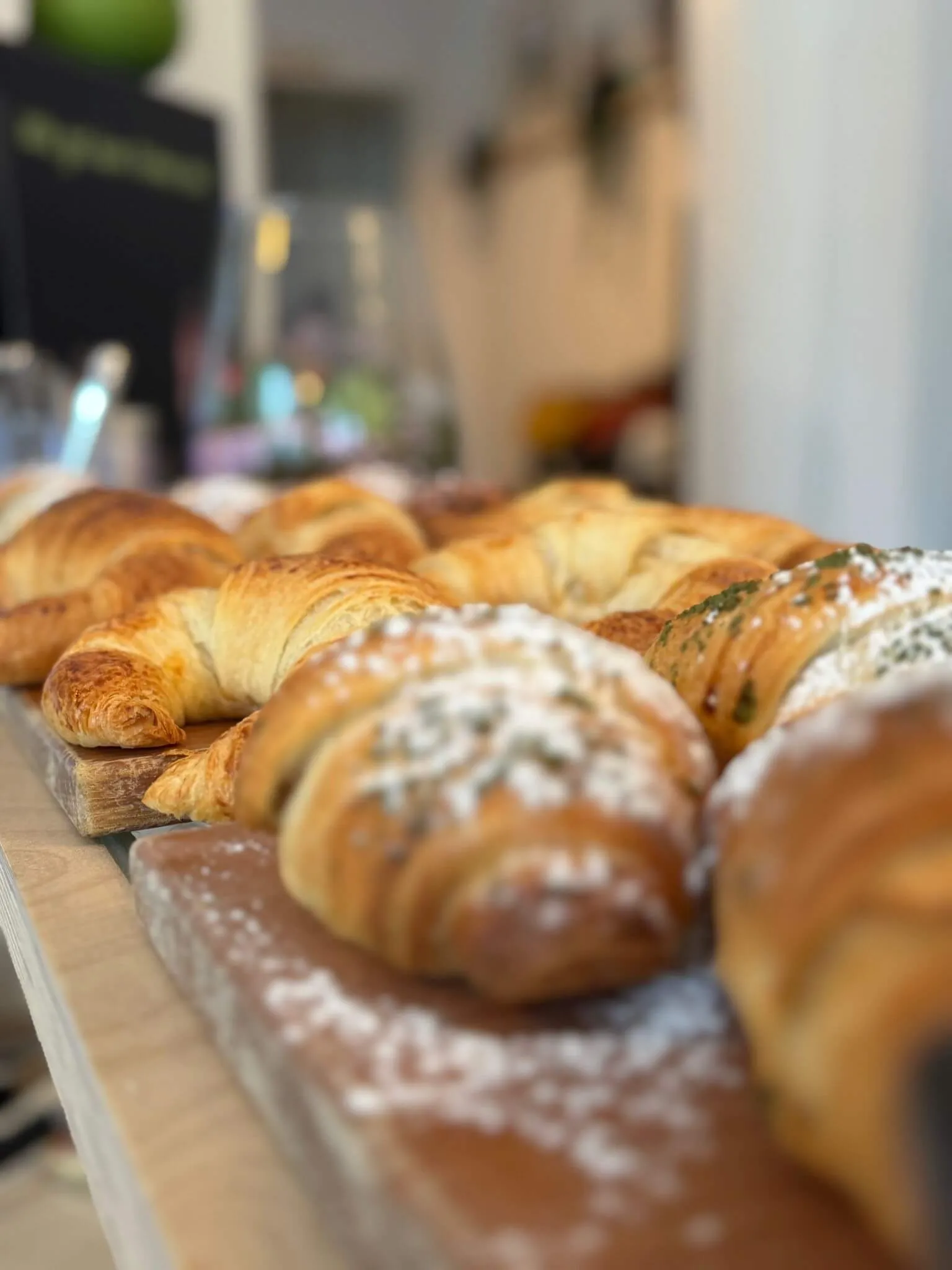 A variety of freshly baked pastries, including croissants and flaky breads, displayed on a wooden table.