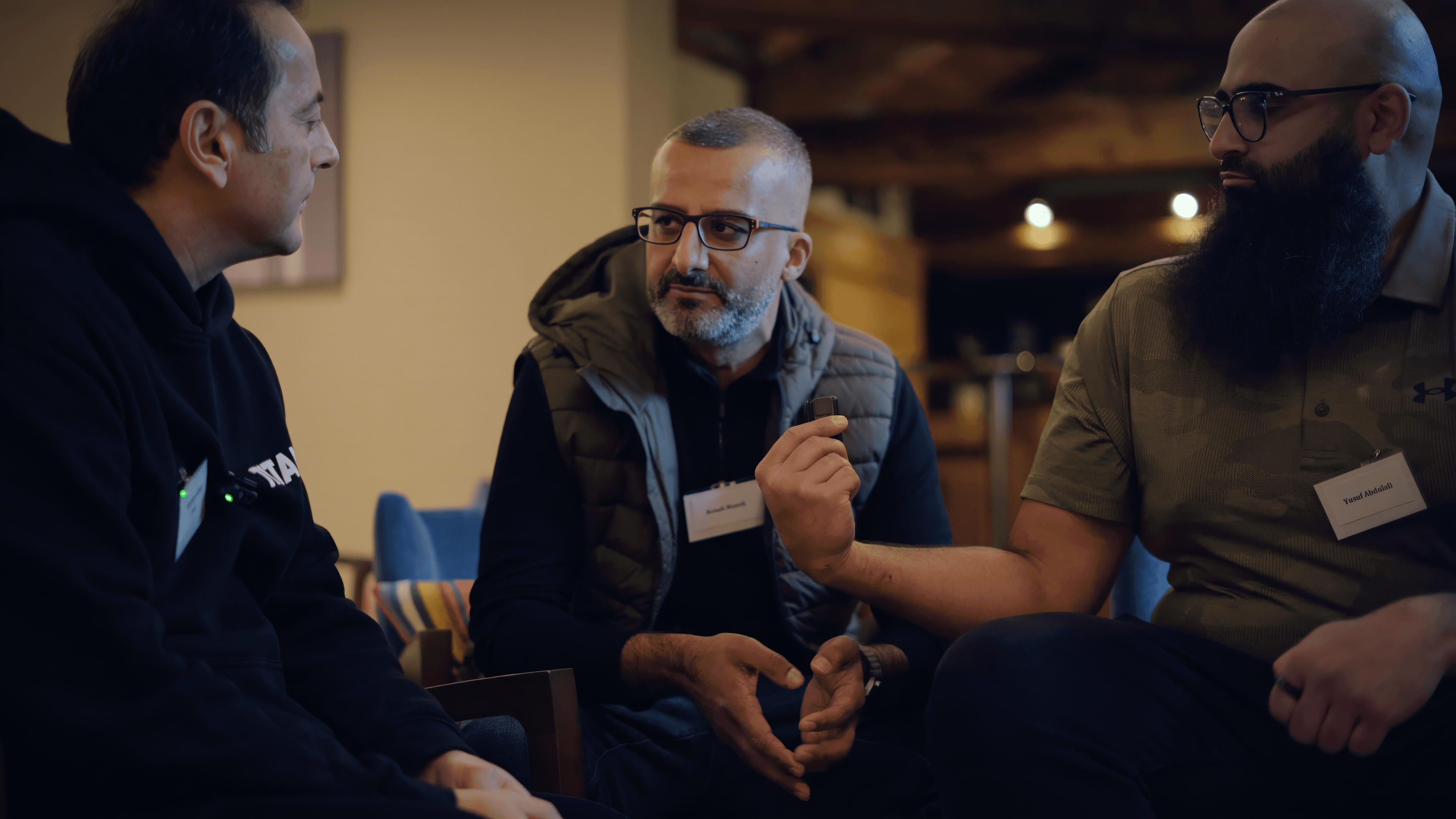 A stylised 3D illustration of three people of different ages and ethnicities looking confused while checking their smartphones. Floating pharmacy icons appear around each phone, suggesting repeated or unexpected pharmacy nomination changes.
