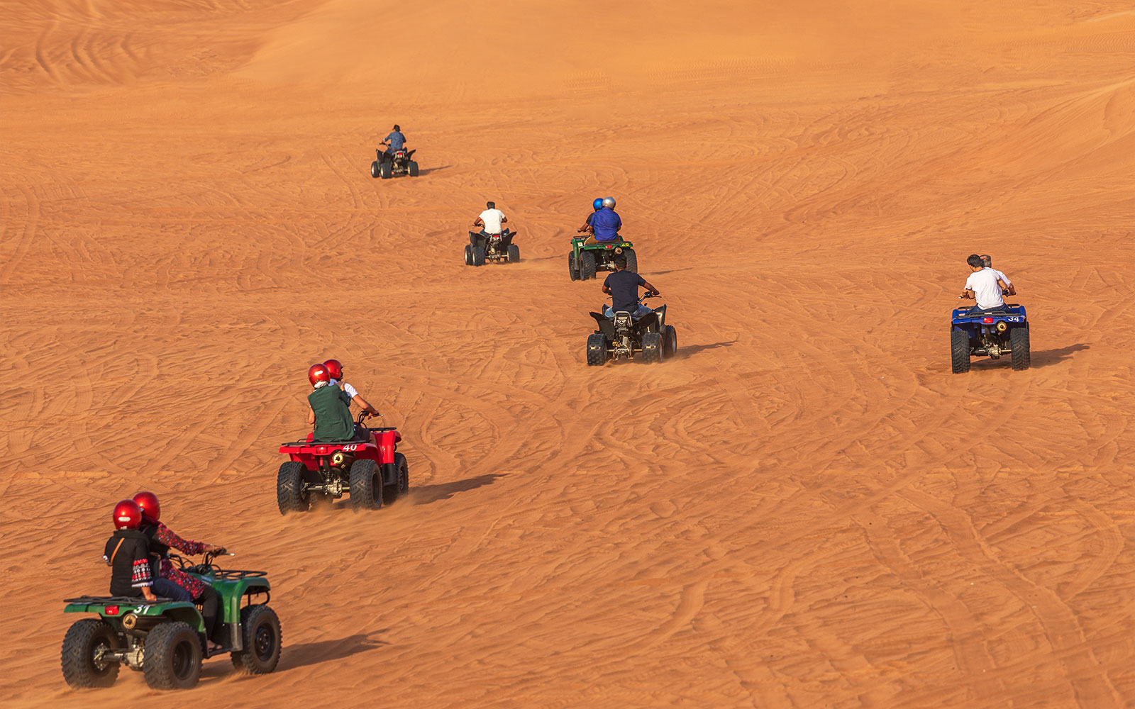 Persone che guidano quad su dune di sabbia durante un safari nel deserto a Dubai.