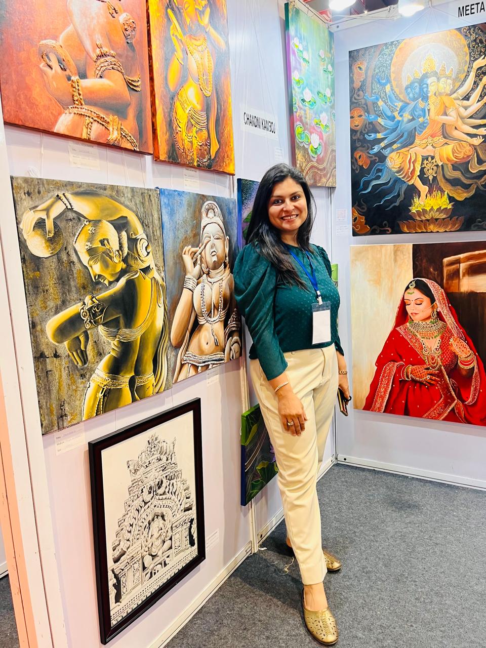 Mrs. Chandni Kamboj, founder of The Creative Pod, standing beside artworks at an art exhibition