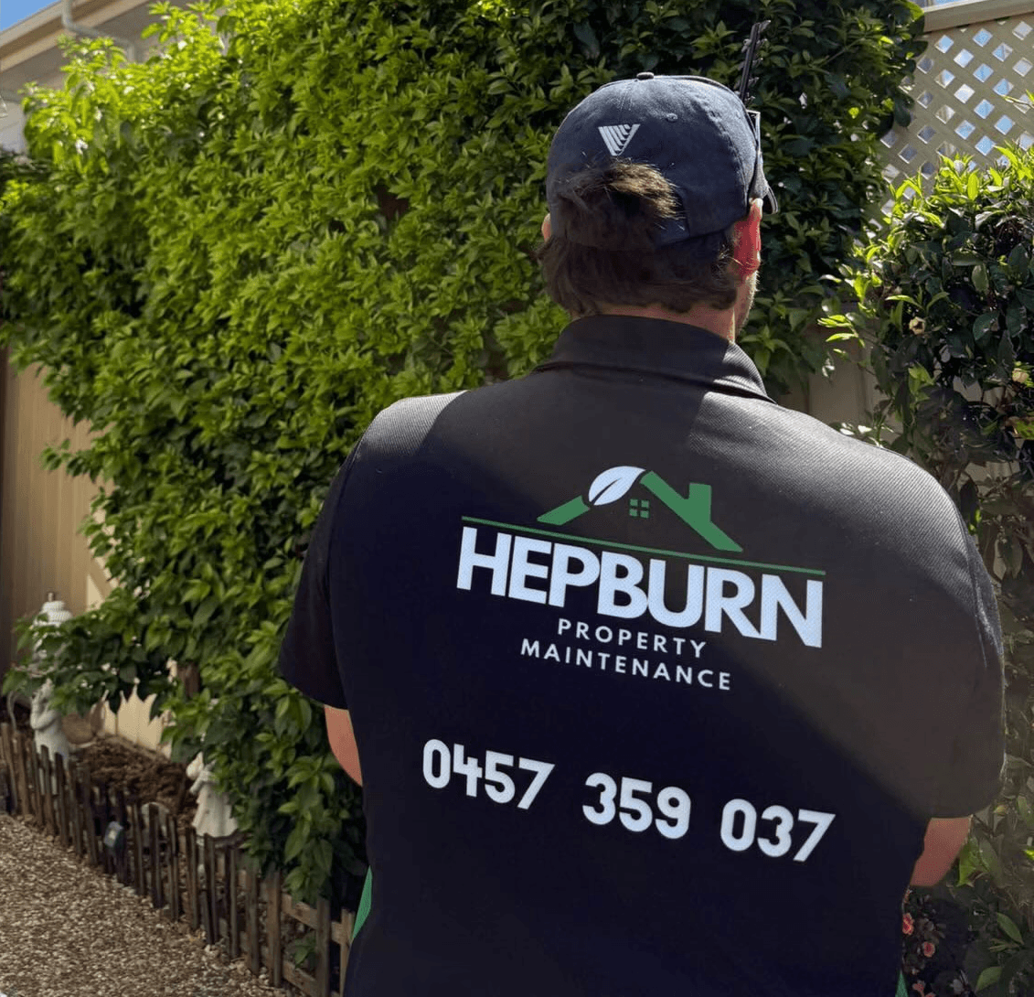 Hepburn Property Maintenance team member assessing overgrown hedge at residential property Gold Coast