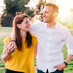 Photo of couple outdoors walking with the sunset in the background.