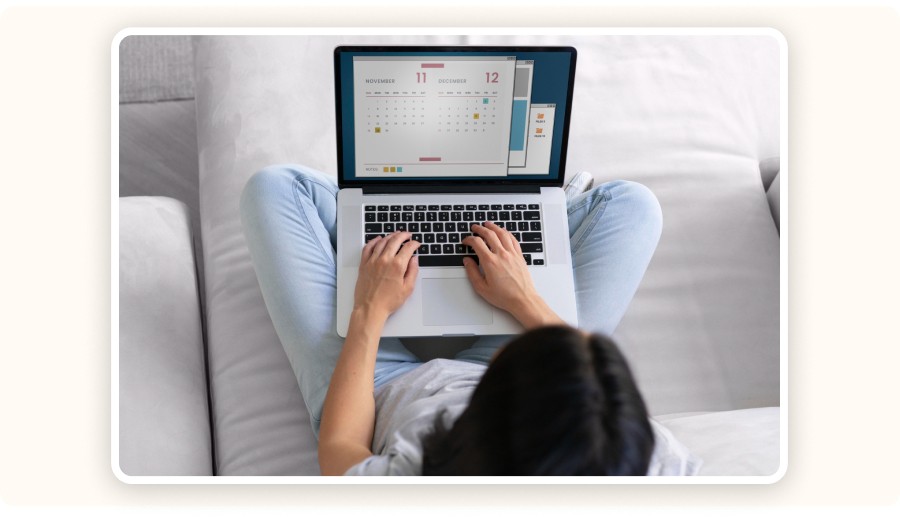 Personne utilisant ordinateur portable avec calendrier en étant assise sur canapé