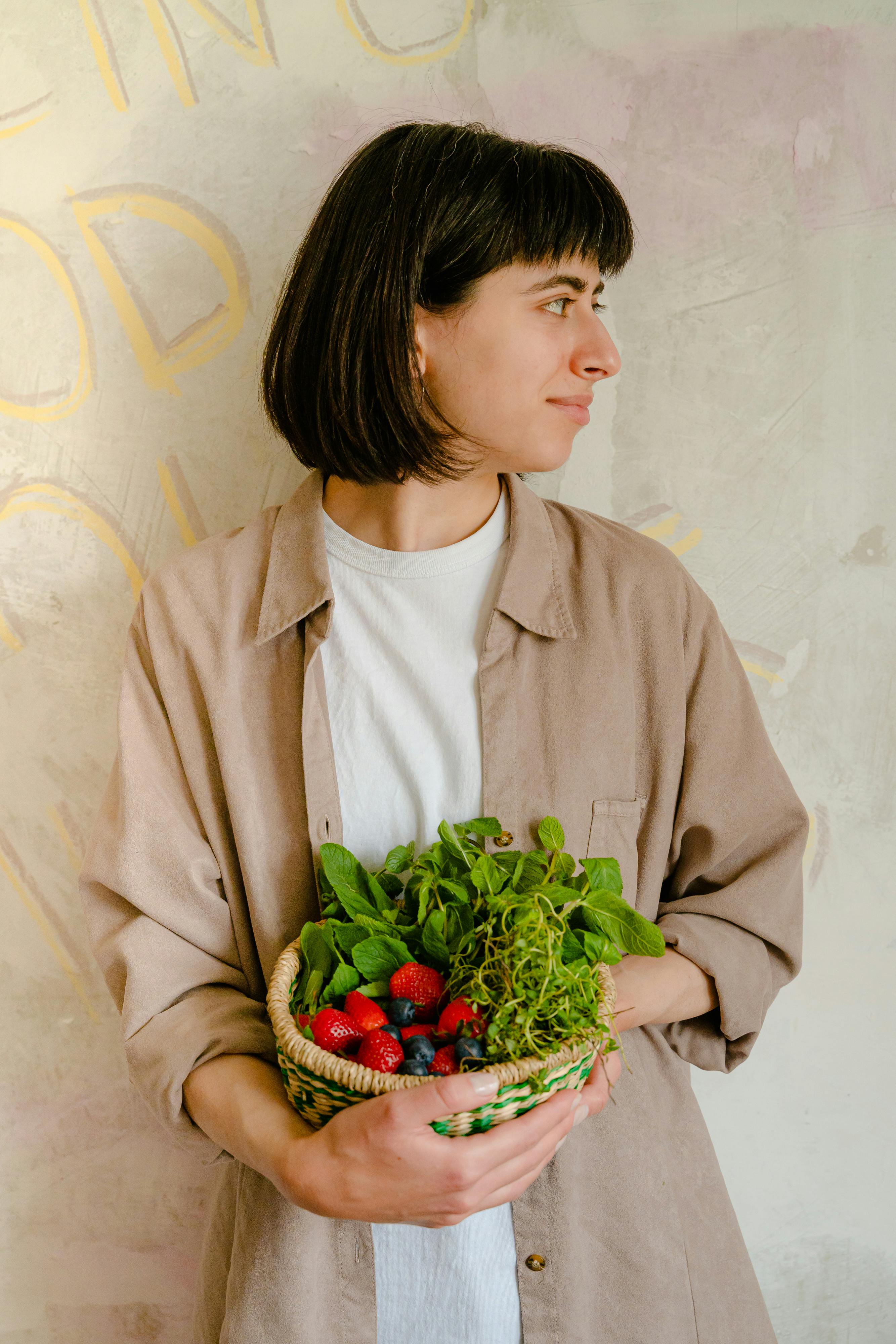 Person holding leafy greens looking sideways indoors