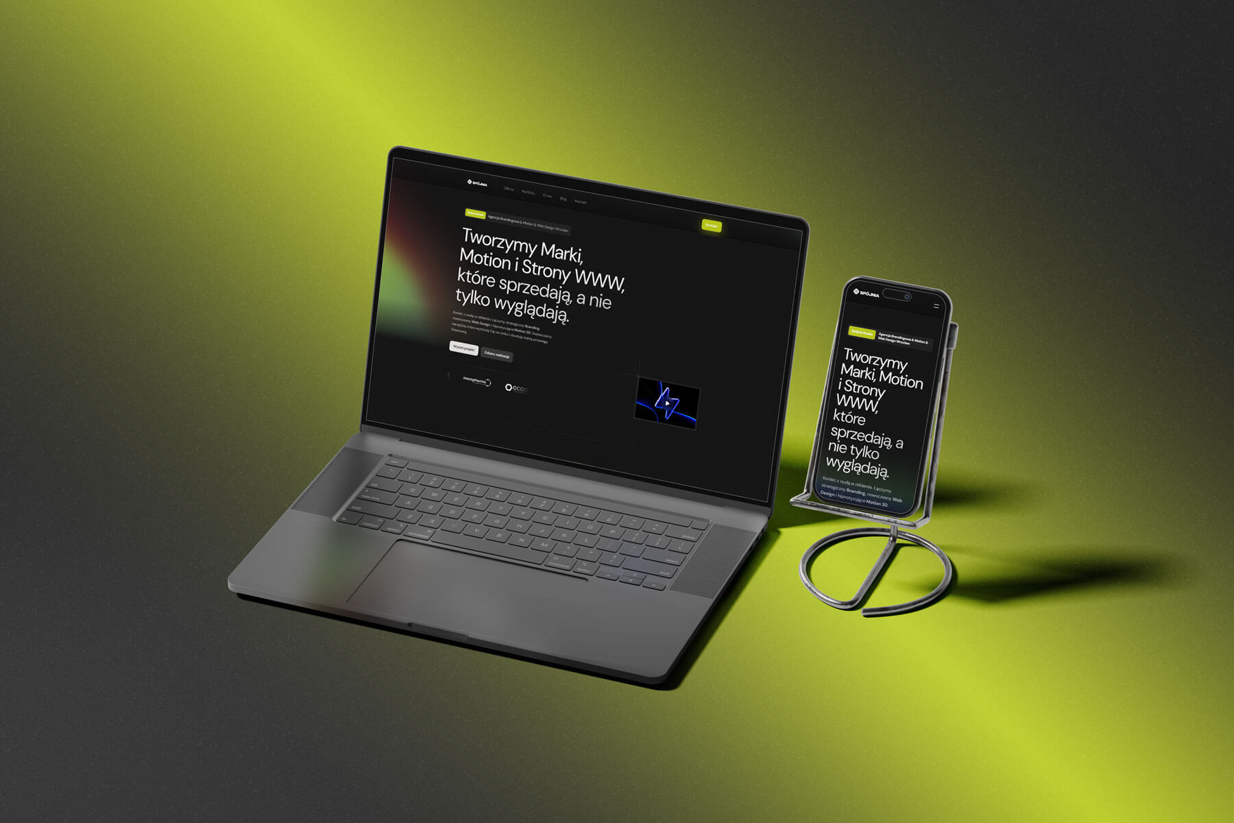 Laptop oraz smartfon z otwartą stroną internetową studia Spójnia prezentującą ofertę projektowania stron www i animacji motion 3D na ciemnym tle z zielonym światłem.