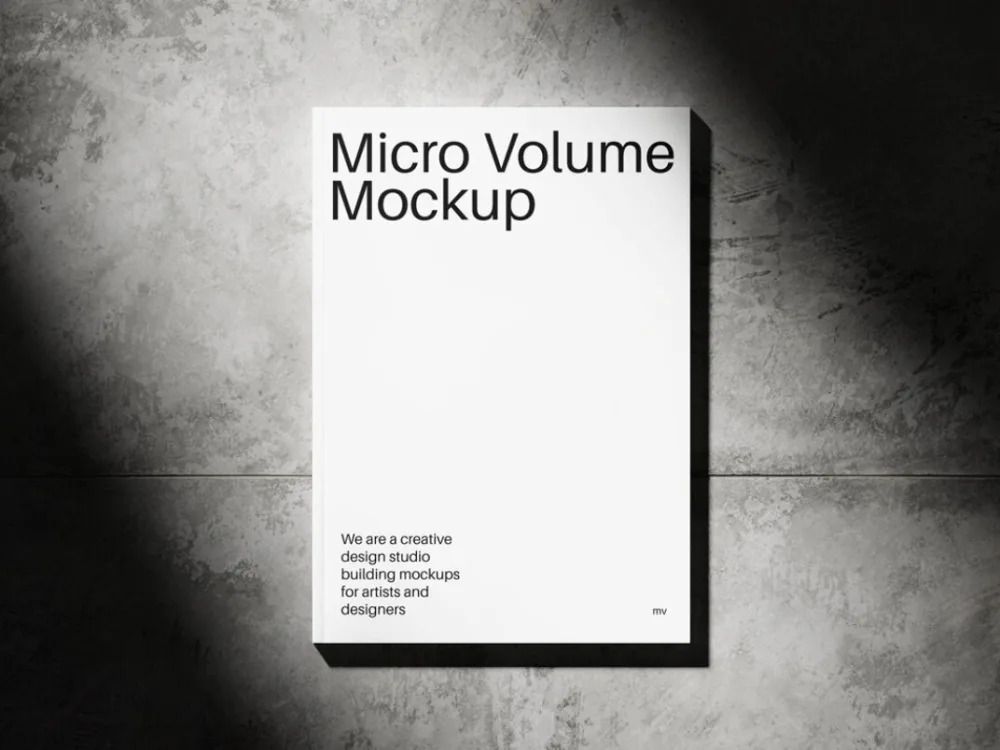 Minimalist book cover mockup against a textured concrete wall with dramatic light and shadow. The white cover reads "Micro Volume Mockup" with a short tagline, ideal for showcasing design concepts.