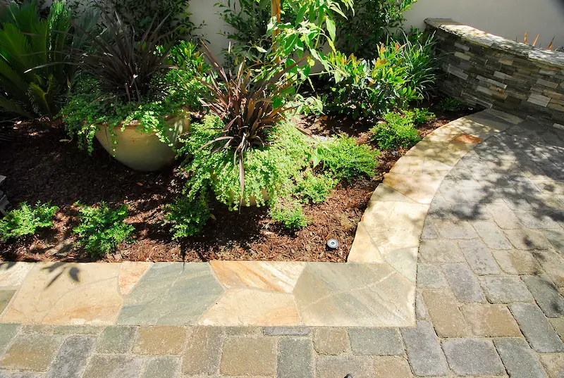 Flagstone path leading through lush greenery with potted plants in Irvine Transitional Modern. Photo by Chris Darnall.