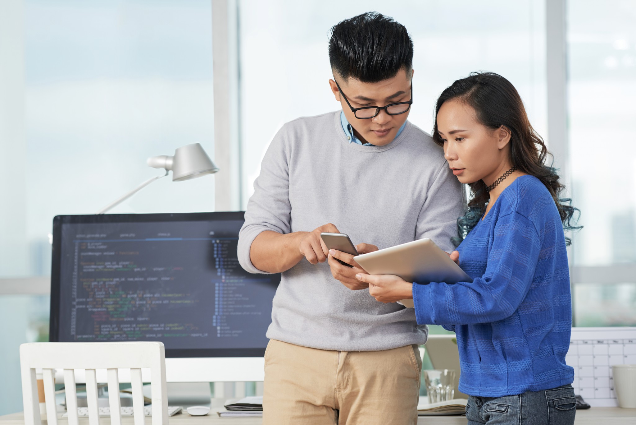 A man and woman stand together in front of a computer, discussing new tools to enhance telecom operations and efficiency.
