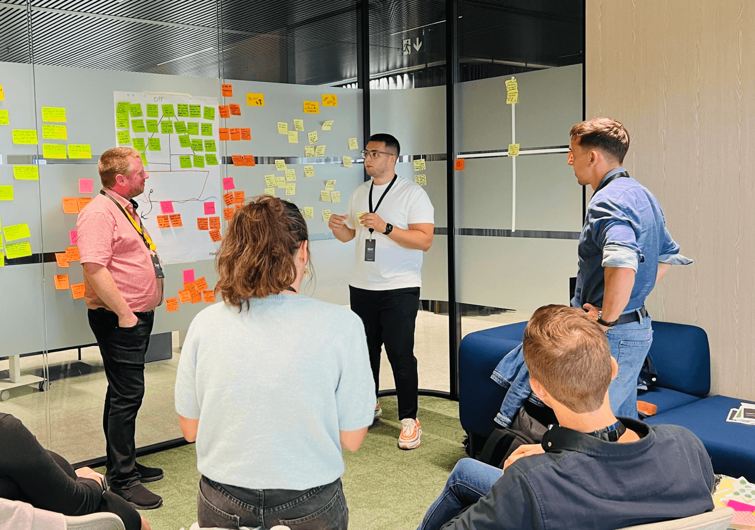 Strategy workshop with participants discussing and mapping ideas on a wall covered with colorful sticky notes