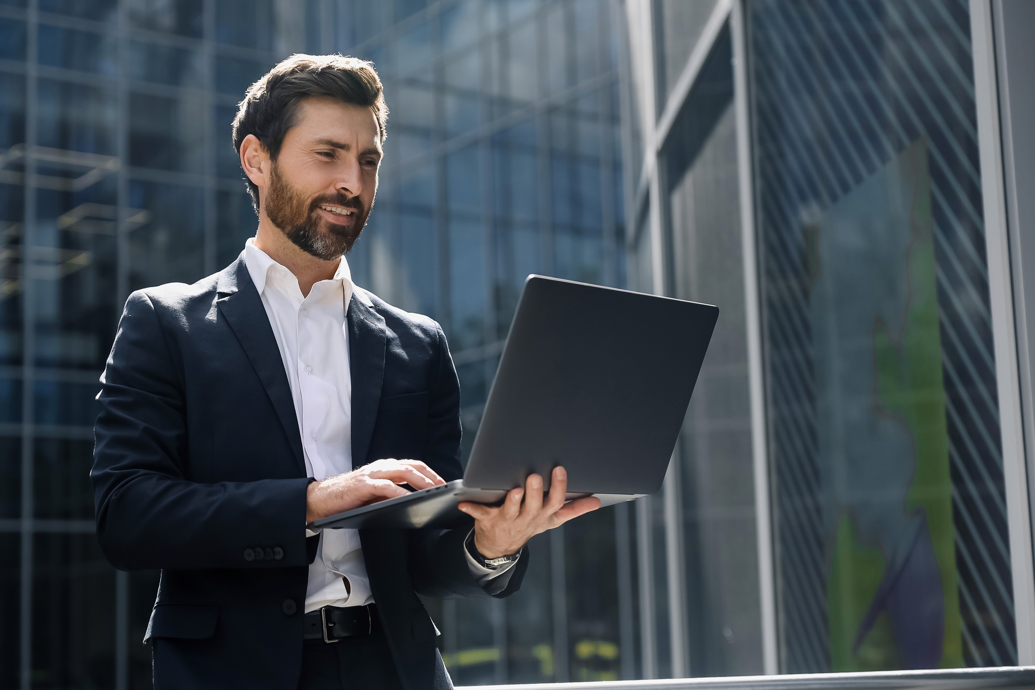 Man in glasses using phone at desk with laptop.