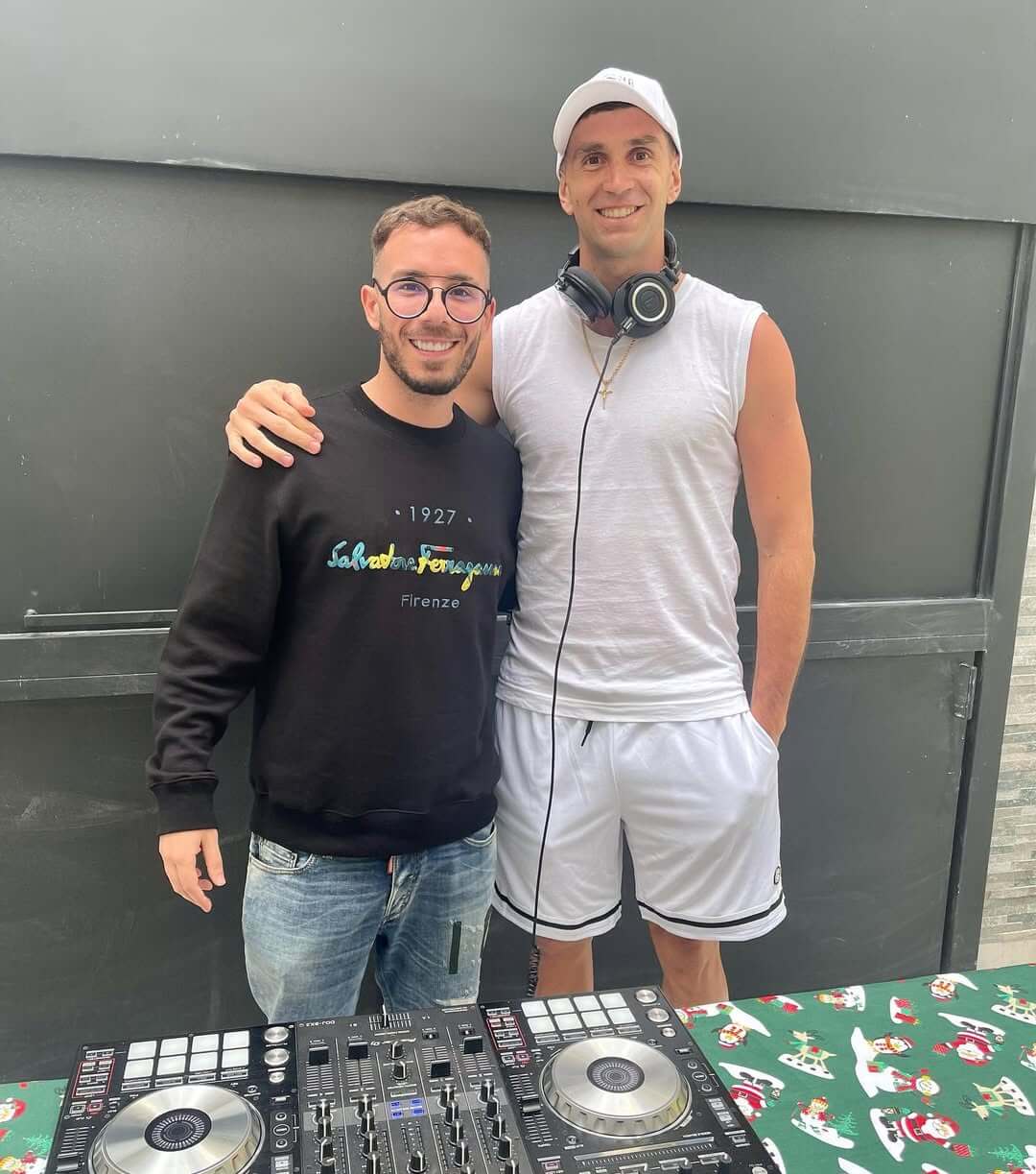 Fer Palacio junto a Dibu Martínez en un ambiente relajado, con un DJ set en el fondo.