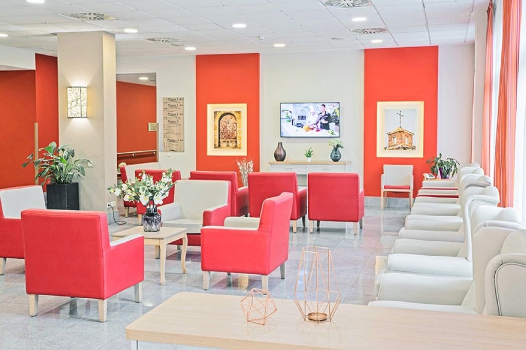 Vibrant interior common area with bold red accent walls, contemporary red seating furniture, bright natural light, white ceiling, and modern design elements