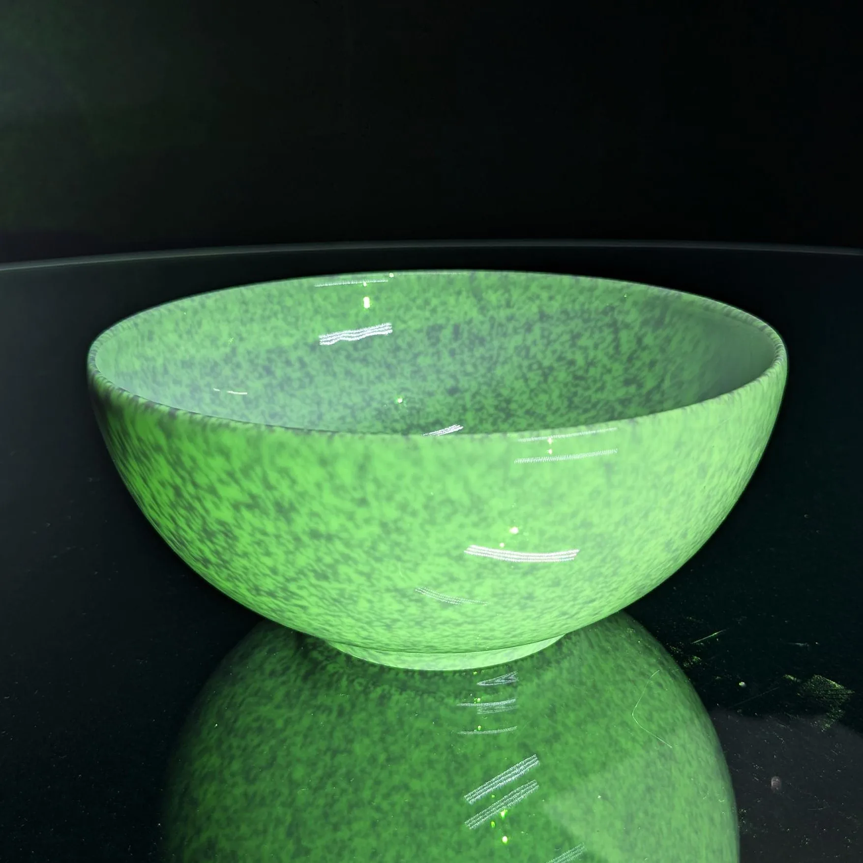 White bowl on glass turntable with green pattern projection projected onto it, making the plain white surface visually noisy.